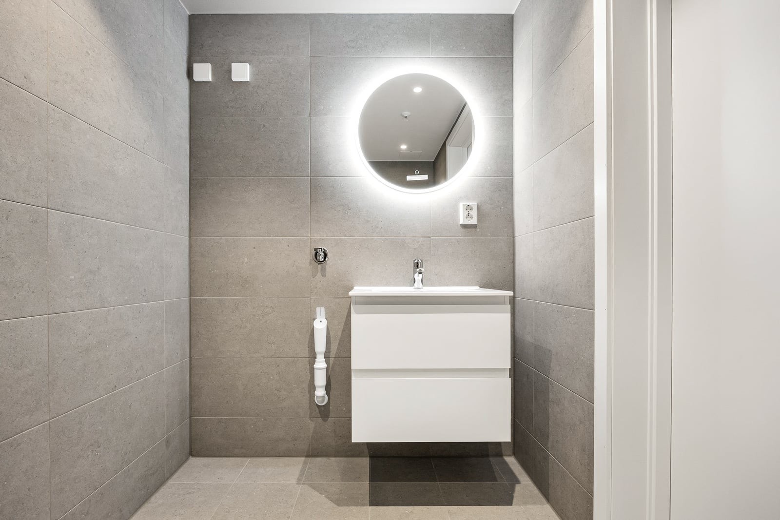 Badet er innredet med servant, vegghengt toalett og speil med integrert belysning. Galleribilde