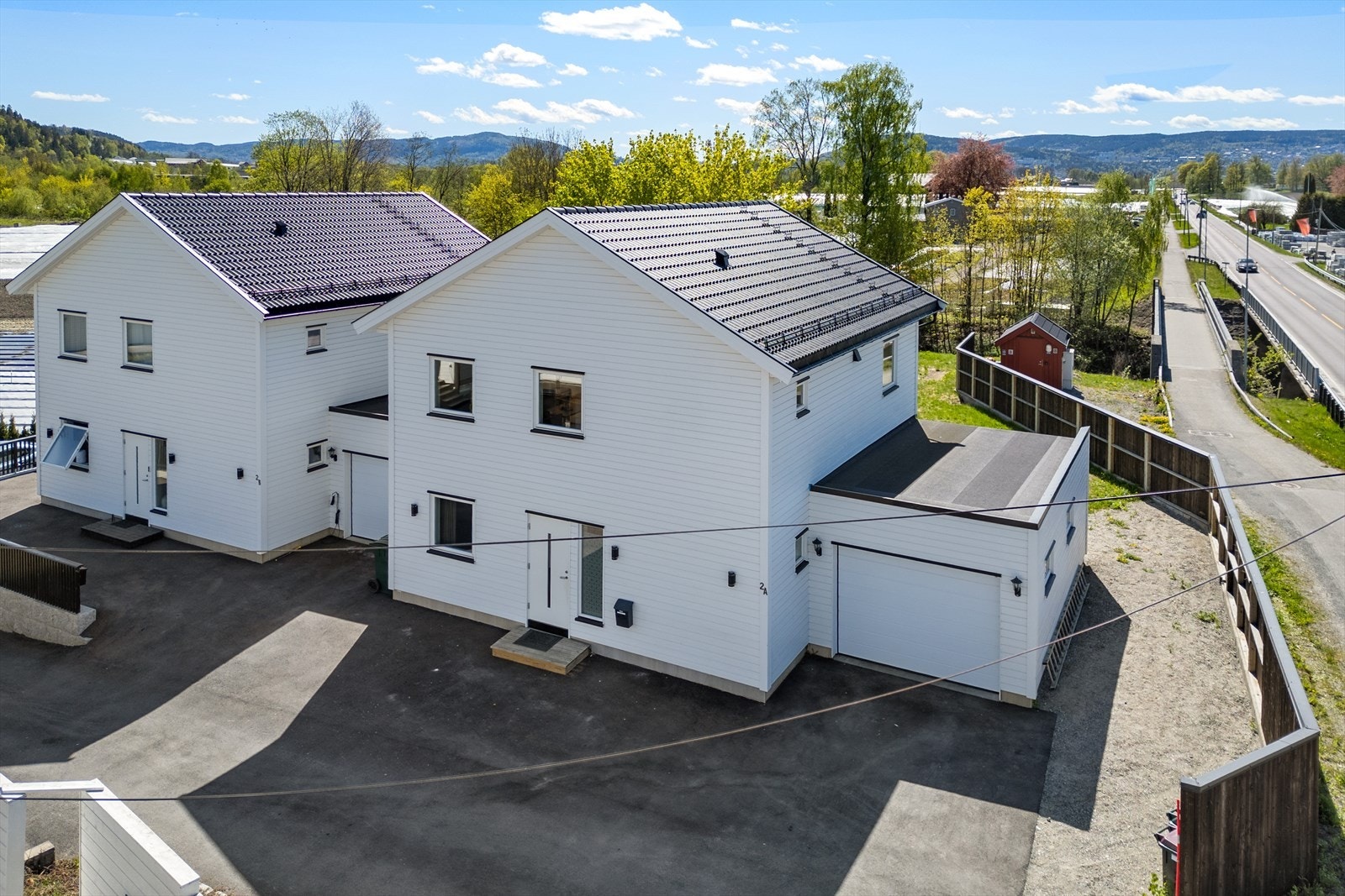 Eiendommen inkluderer en stor garasje med innlagt strøm og automatisk portåpner, samt en asfaltert gårdsplass. Galleribilde