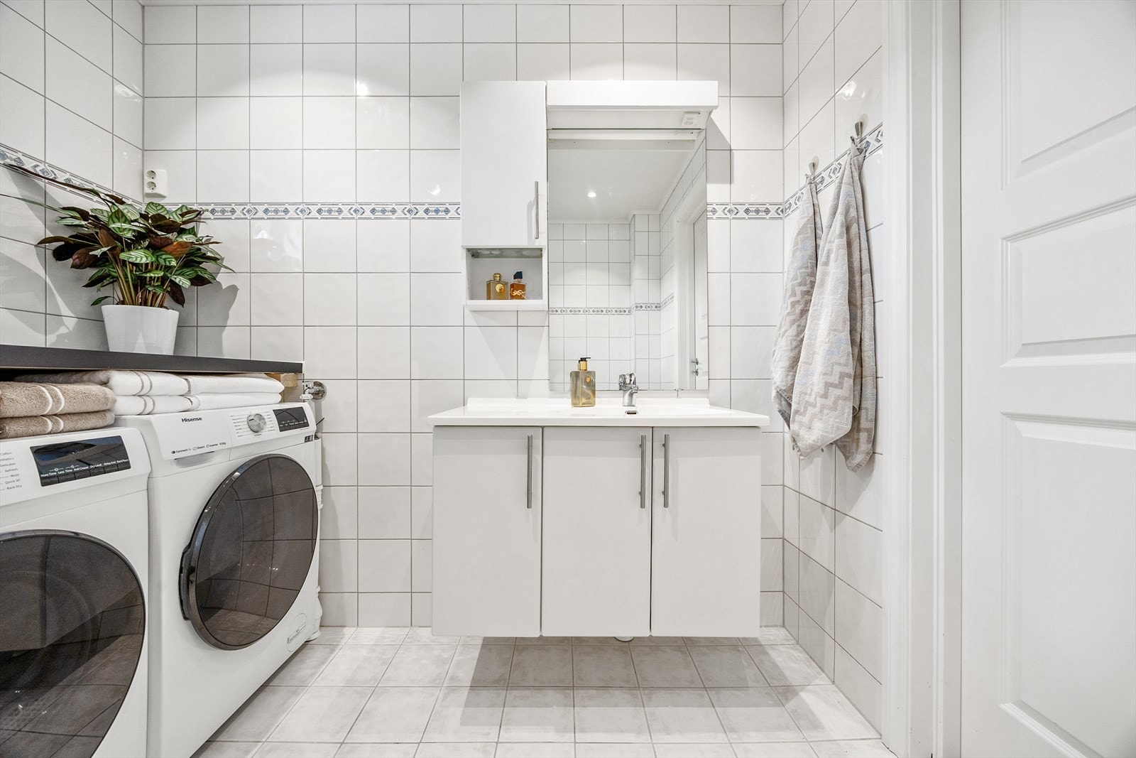 Badet er innredet med servant i baderomsinnredning, dusjhjørne, toalett og opplegg/plass for vaskemaskin og tørketrommel. Galleribilde