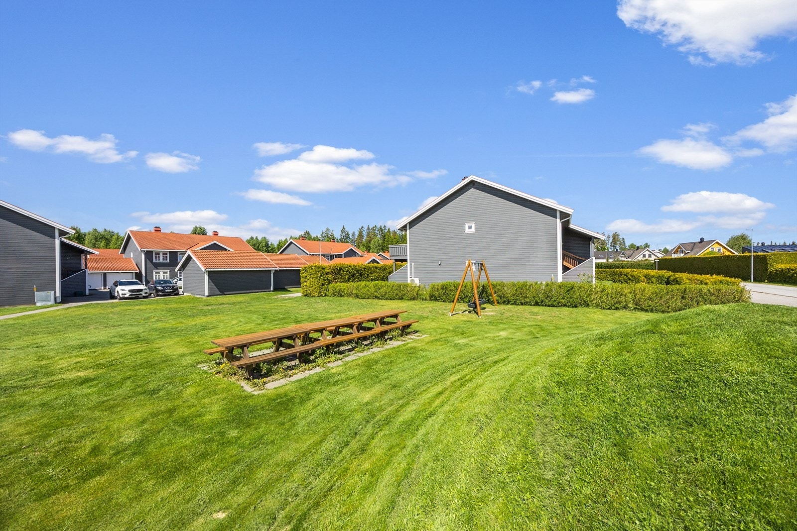 Lekeplass med plen, husker og sittegruppe på fellestomten. Galleribilde