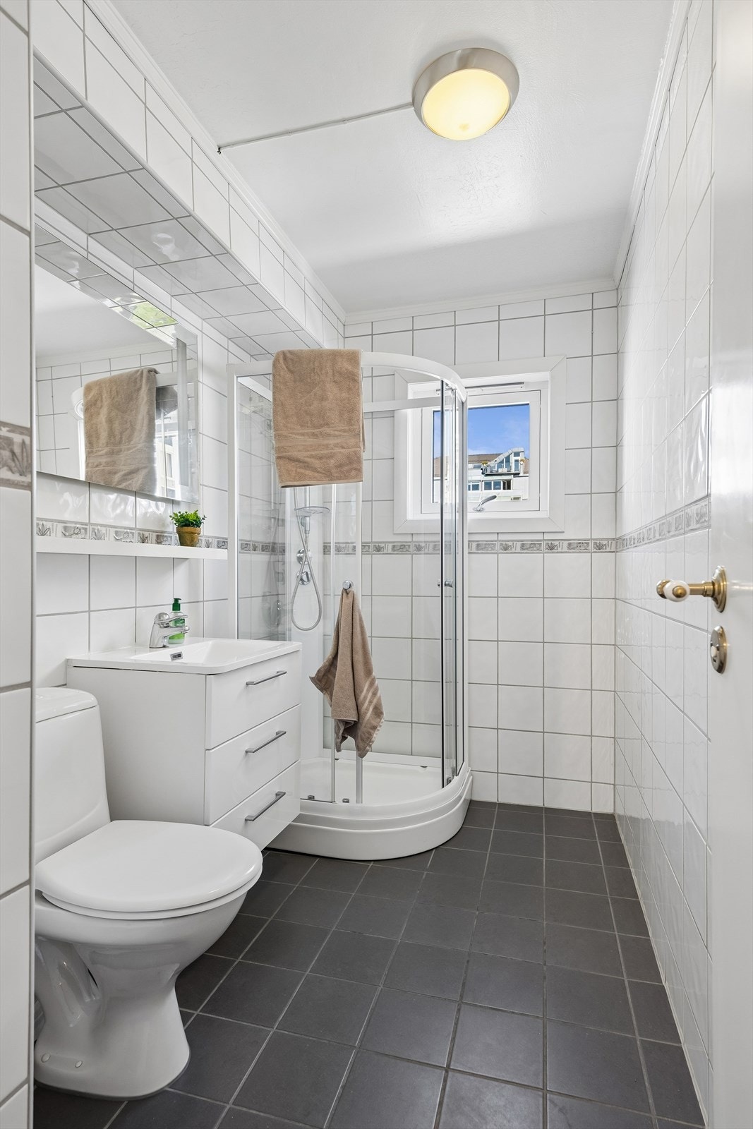 Badet har flislagt gulv med elektriske varmekabler og et praktisk dusjkabinett. Galleribilde