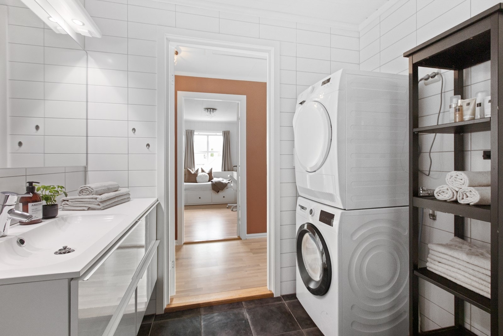 Badet er utstyrt med dusjhjørne, servantinnredning og har opplegg for vaskemaskin. Galleribilde