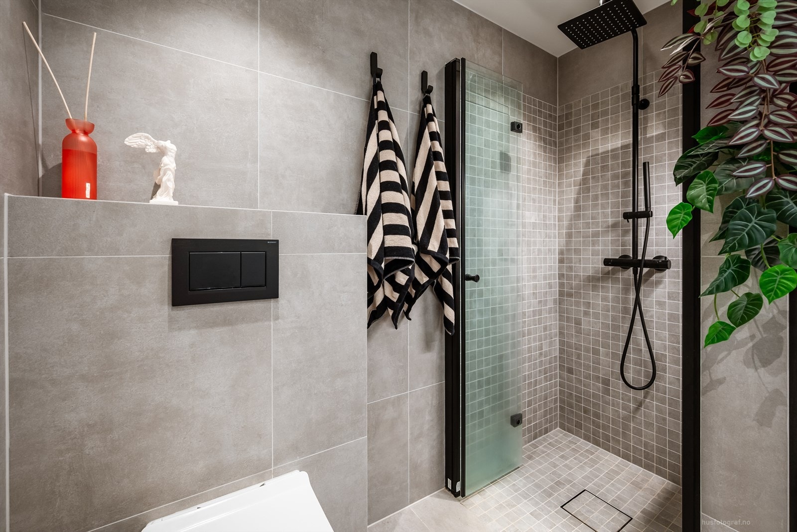 Detaljer fra badet med vegghengt toalett og dusjhjørne med moderne armatur. Galleribilde