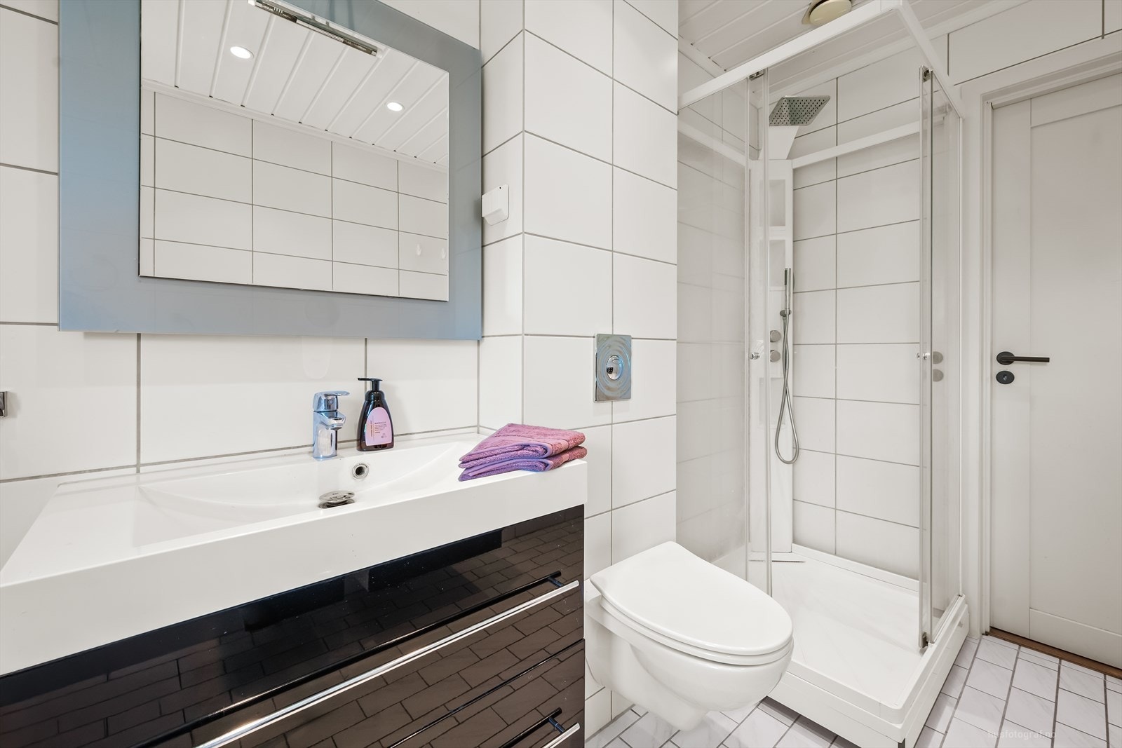 Badet har flislagt gulv med varmekabler, vegghengt toalett og elektrisk styrt vifte. Galleribilde