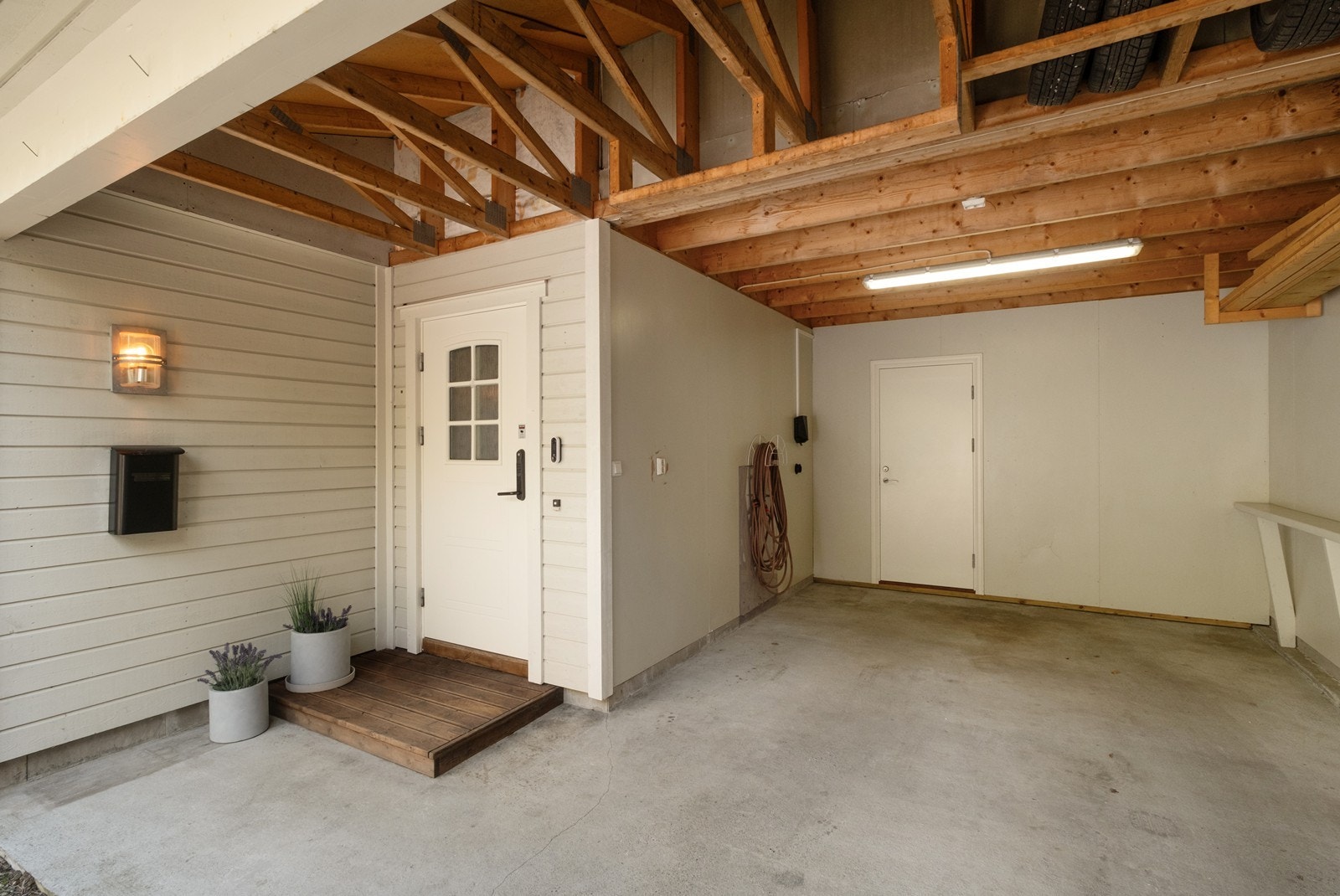 Carport med elbillader gir god parkering under tak, og med inngangspartiet i carportrn kan man her gå tørrskodd fra bilen og inn i boligen, uansett vær. Galleribilde