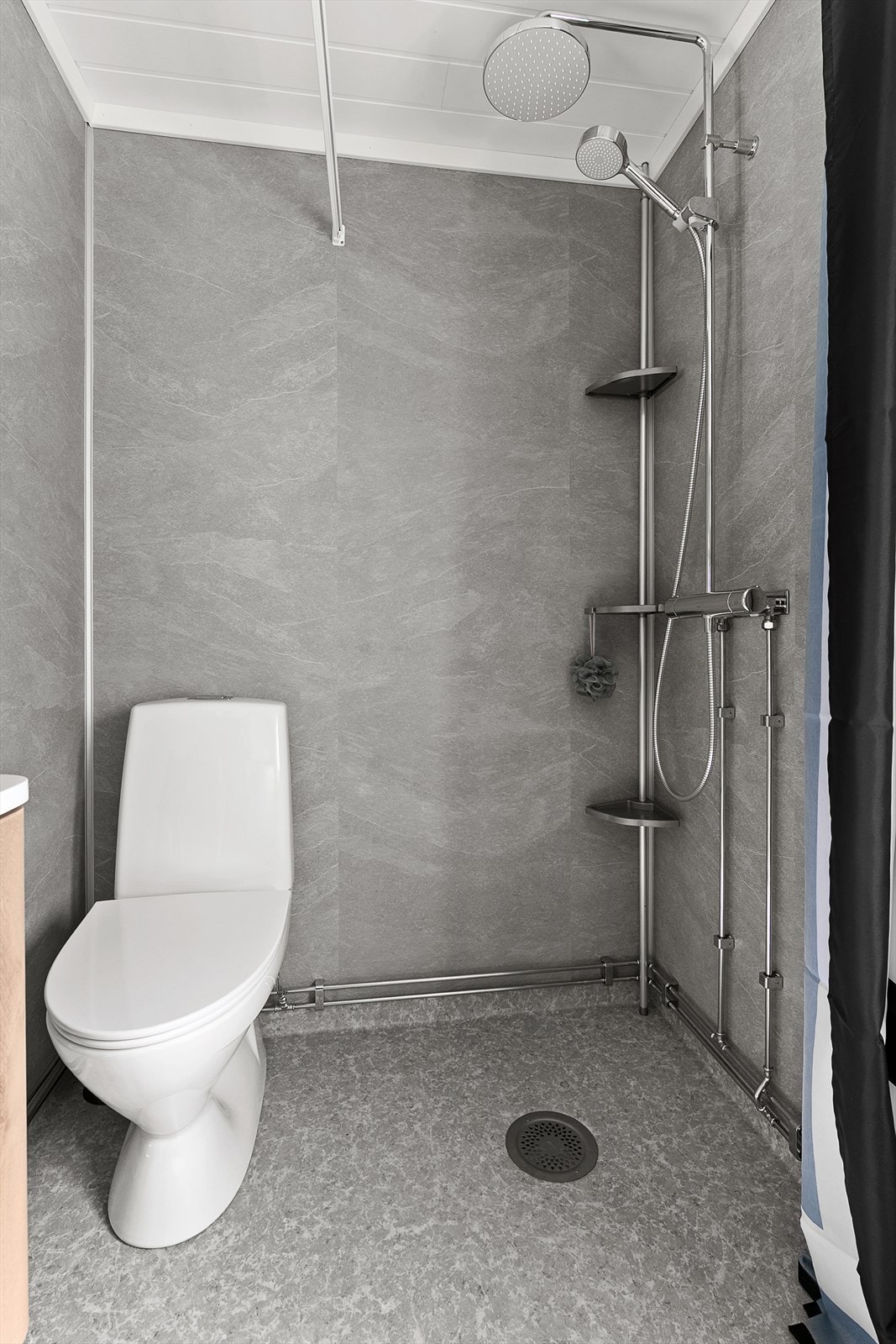 Badet inneholder wc, dusjhjørne og servant med underskap. Galleribilde