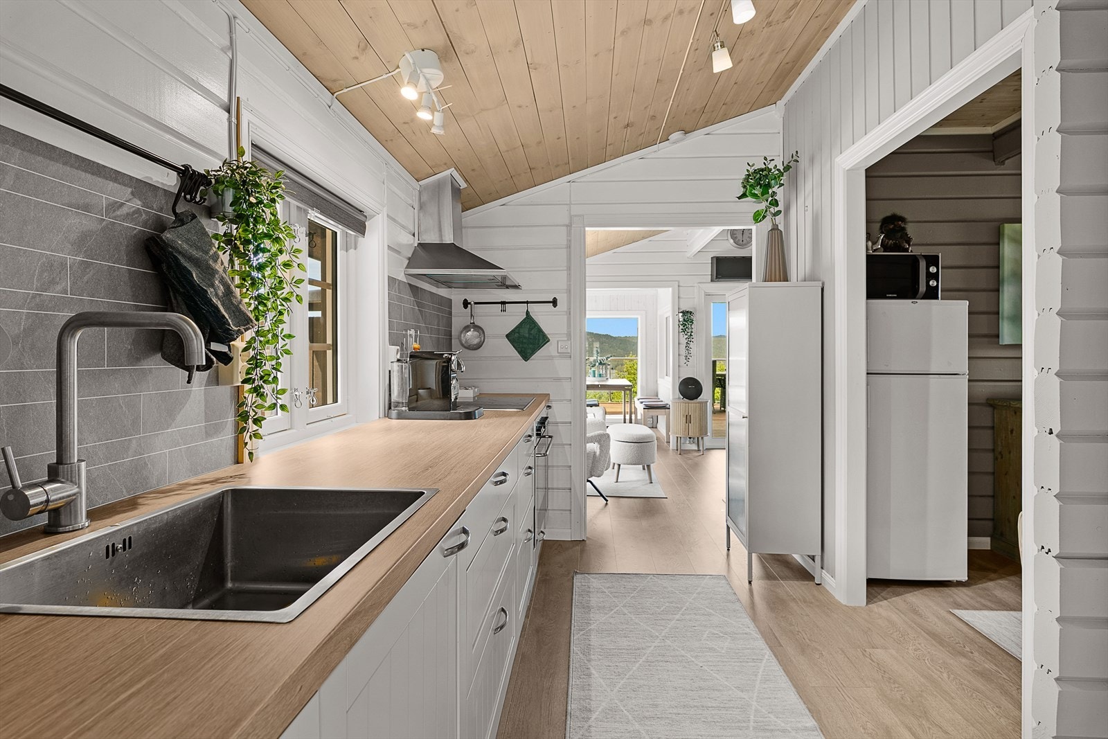 Innredningen er fra IKEA og har hvite profilerte fronter, laminert benkeplate samt integrert komfyr og platetopp. Kjøleskapet er plassert i gangen. Galleribilde