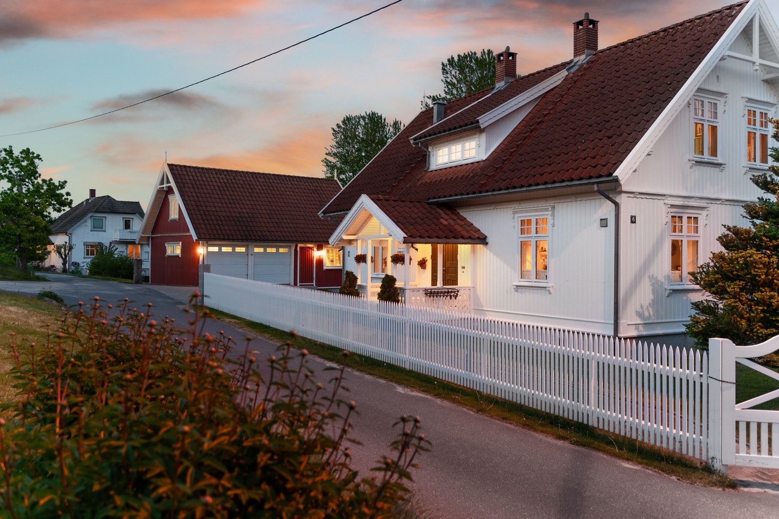 Hvitmalt stakittgjerde rammer pent inn hagen mot sør og vest. Galleribilde