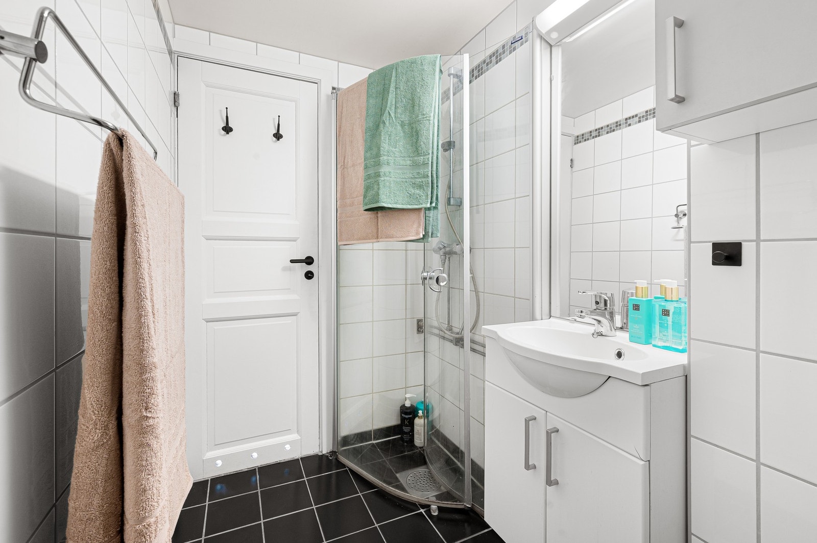 Badet har dusjhjørne, og er utstyrt med gulvmontert toalett og vegghengt servantinnredning. Galleribilde