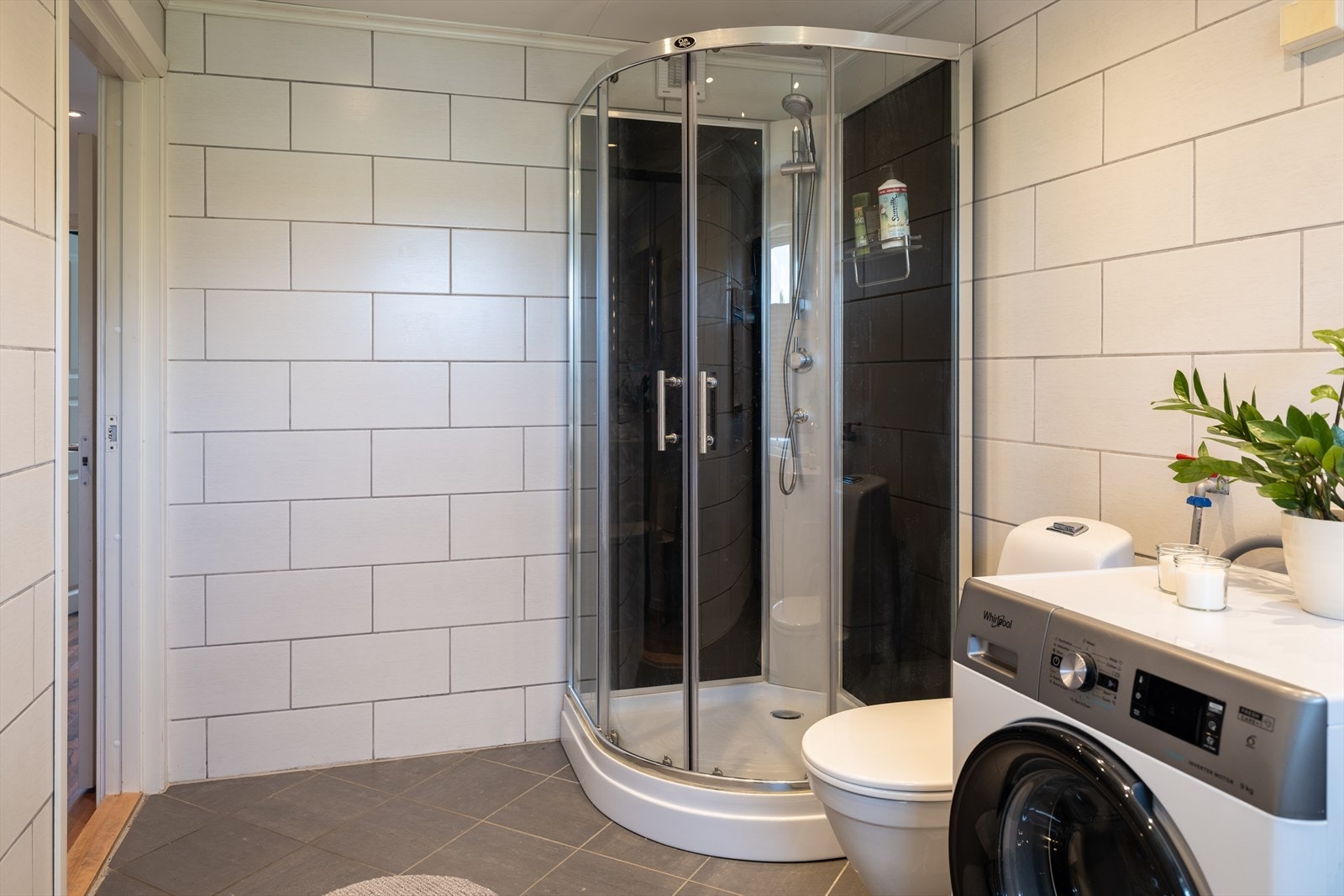 Videre byr badet på vegghengt servantinnredning, dusjkabinett, gulvstående toalett og opplegg for vaskemaskin. Galleribilde