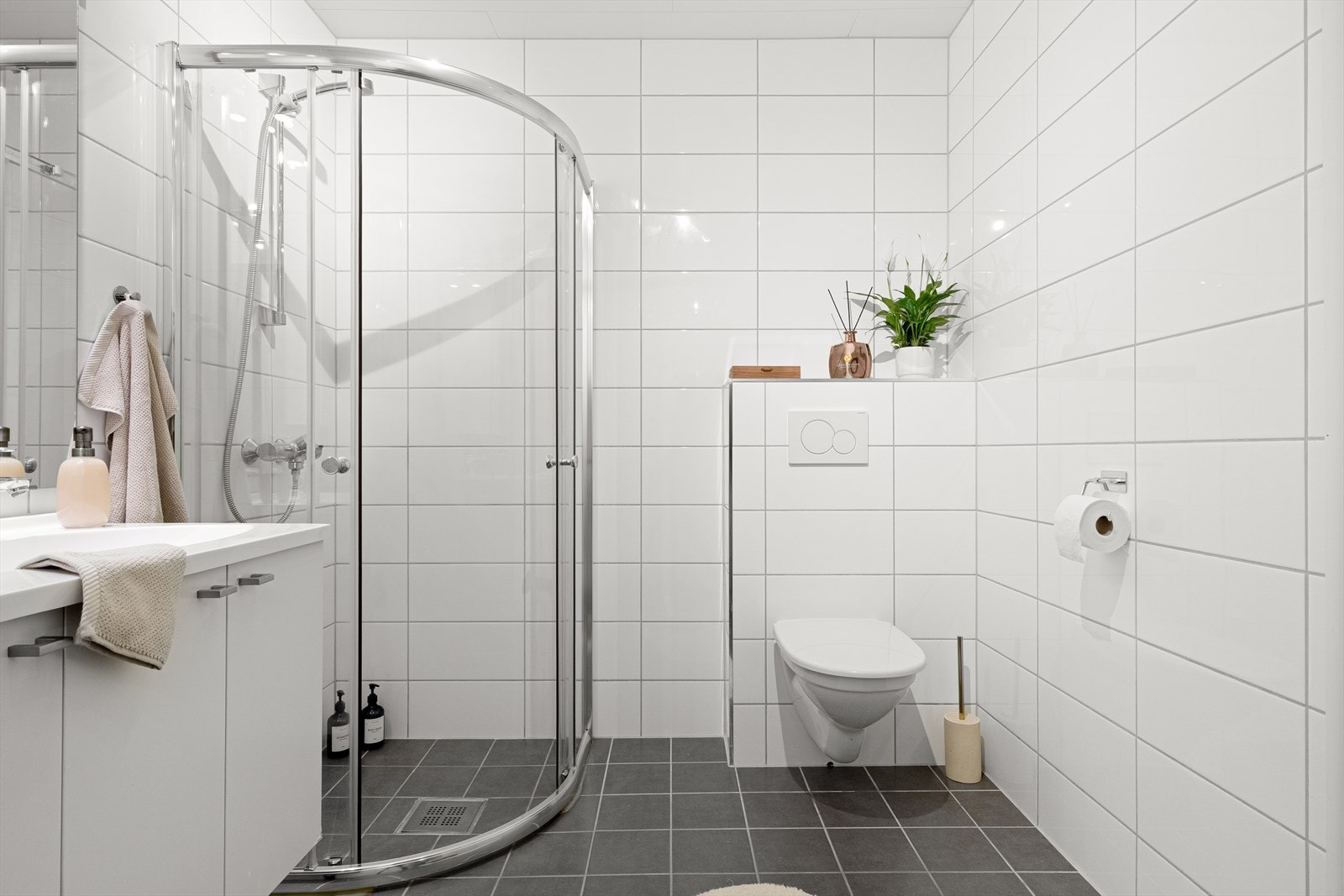 Badet er på 5,9 kvm og er innredet med toalett, dusjhjørne og nedfelt porselenvask i baderomsmøbel. Galleribilde