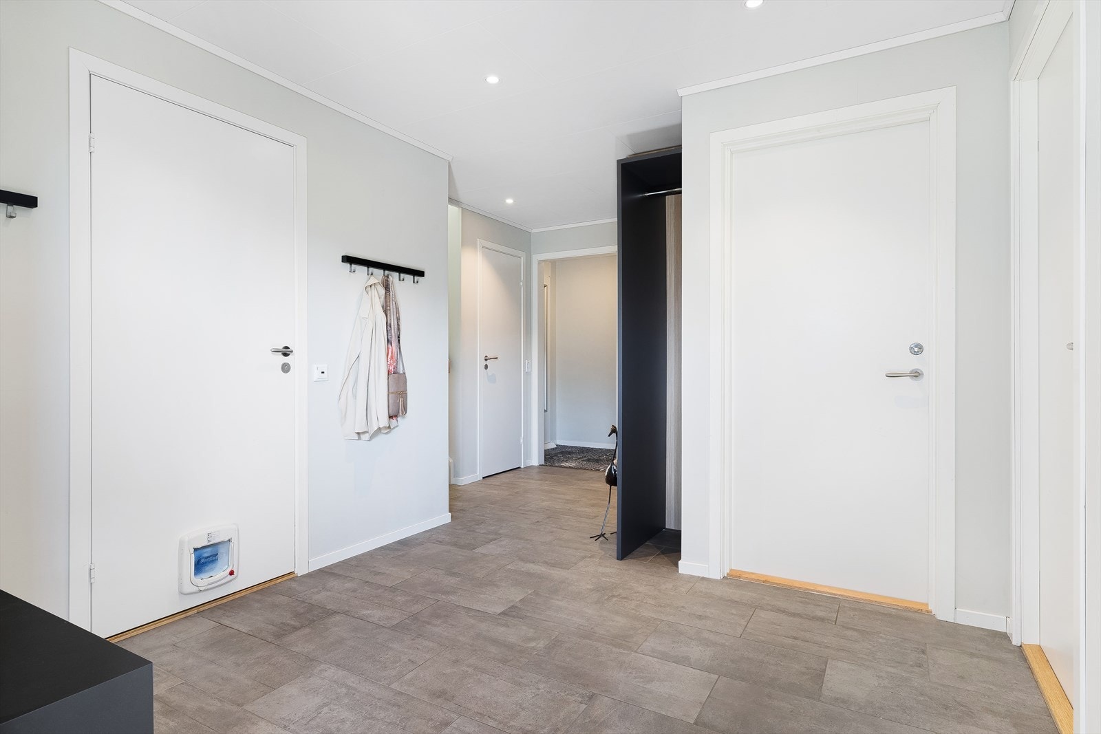 Gjennomgående materialvalg med malte plater på veggene og fliser på gulvet i gangen. Galleribilde