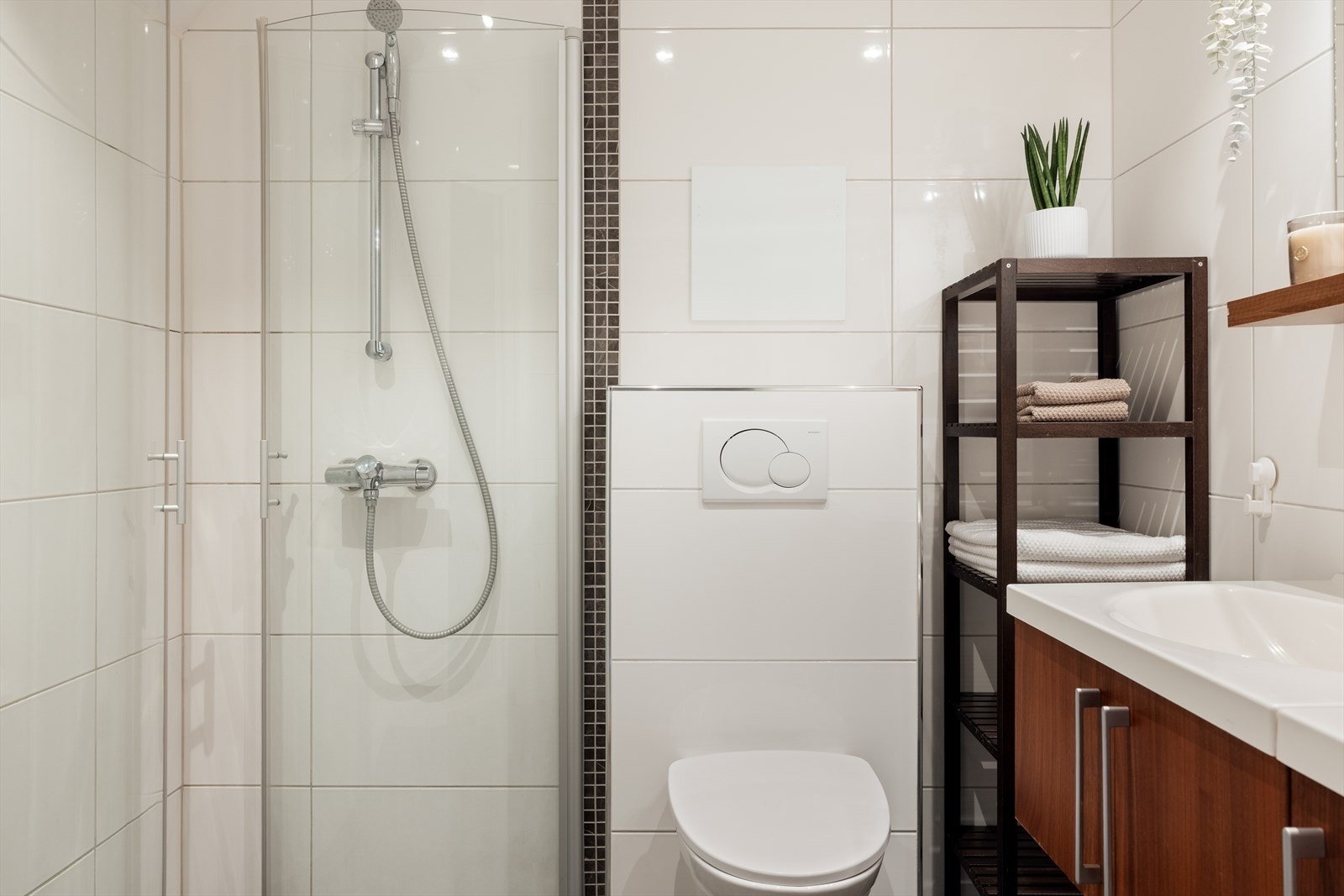 Badet er funksjonelt innredet med nedfelt servant i baderomsinnredning, veggmontert toalett og dusjvegger. Galleribilde