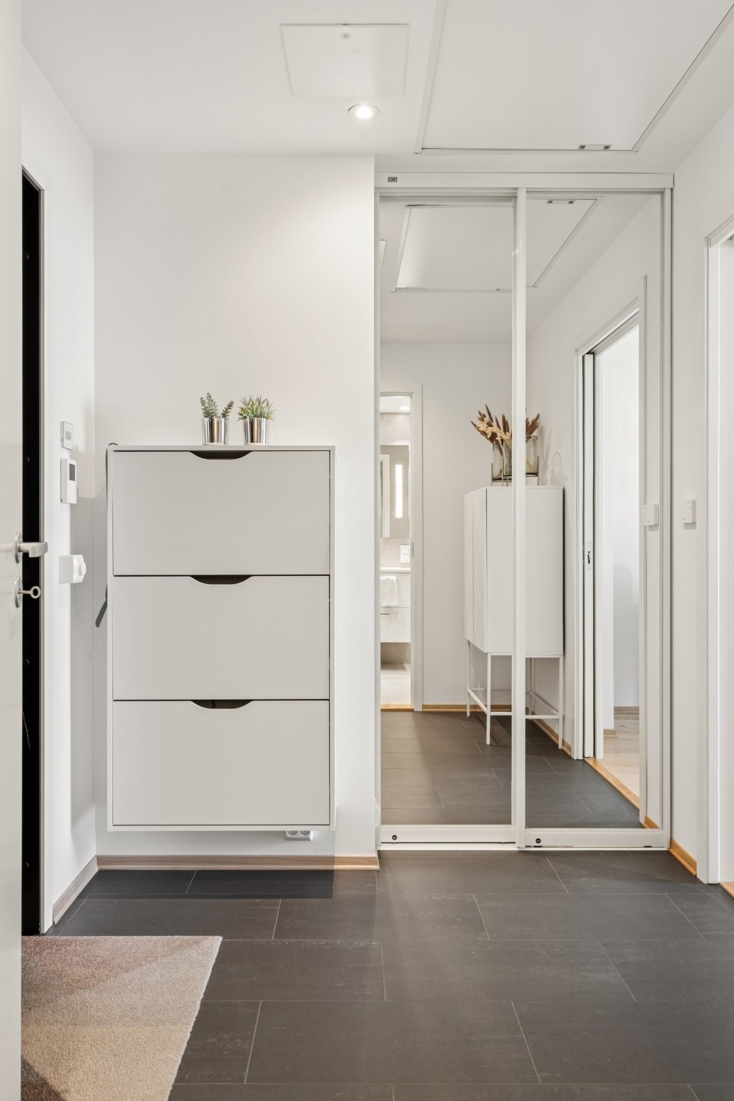En skyvedørsgarderobe med speilfront i gangen gir rikelig med plass til yttertøy og sko. Galleribilde