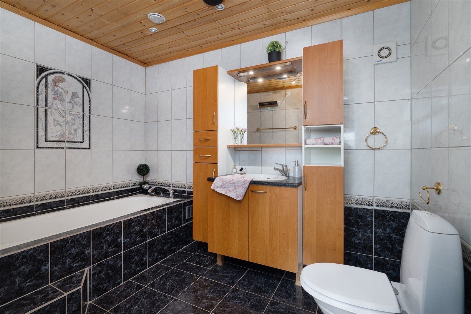 Bad i underetasjen med fliser, innmurt badekar og downlights i taket. Galleribilde
