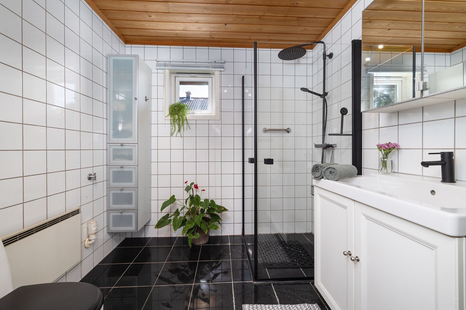 Badet i første etasje har flislagt gulv med gulvvarme. Dusjløsningen med takdusj og glassvegger ble montert i 2024. Galleribilde