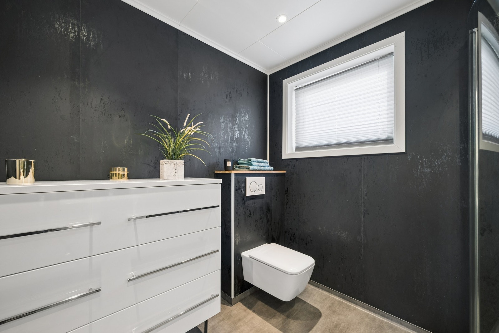 Badet er utstyrt med vegghengt toalett og et romslig dusjkabinett. Galleribilde