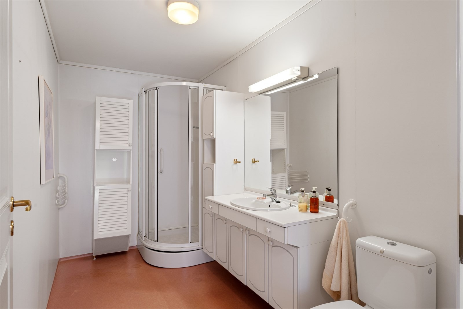Romslig bad med belegg på gulv og gulvvarme. Badet er innredet med dusjkabinett, wc og seksjon med vask Galleribilde