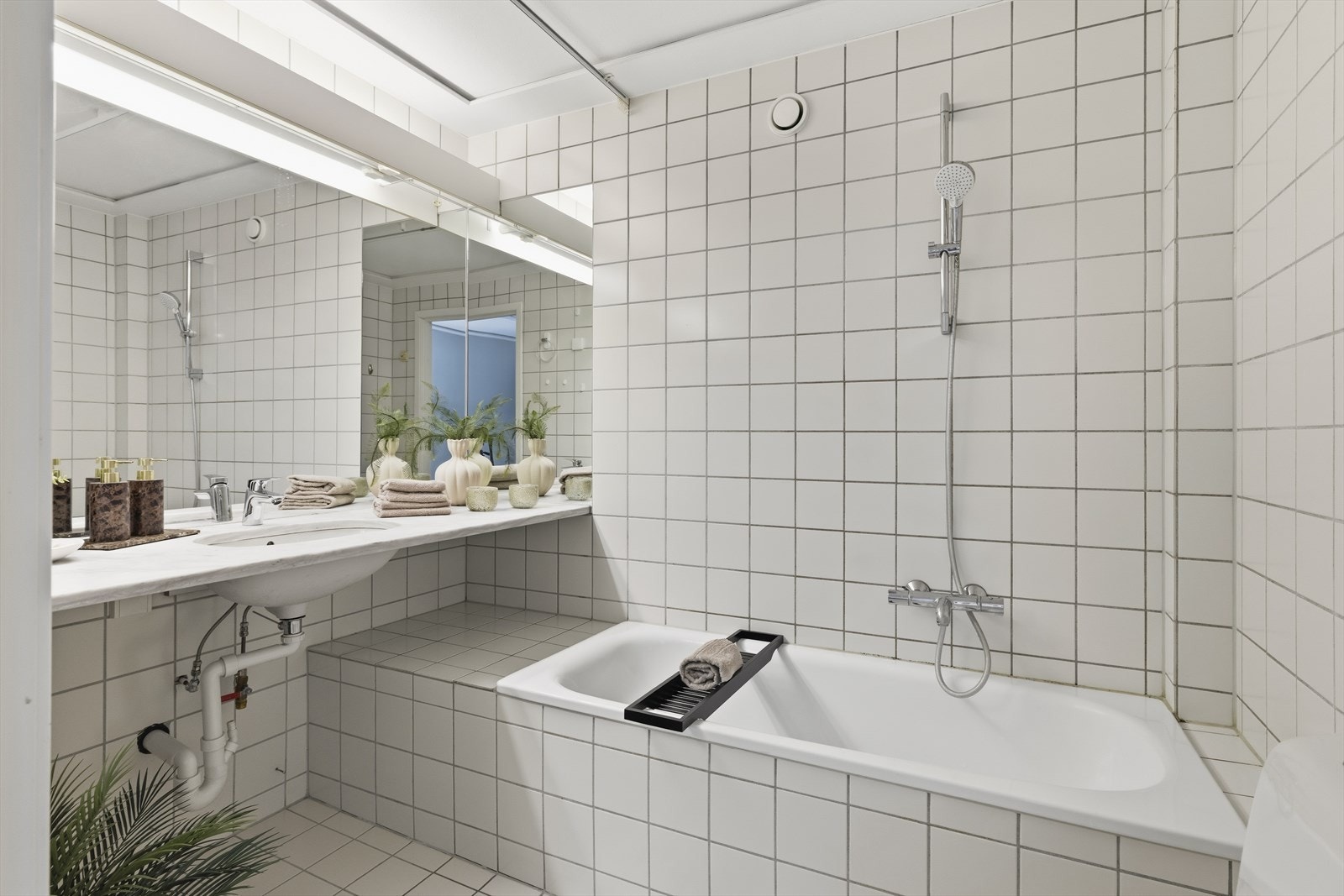 Det er innmurt badekar og opplegg til vaskemaskin under benken. Galleribilde