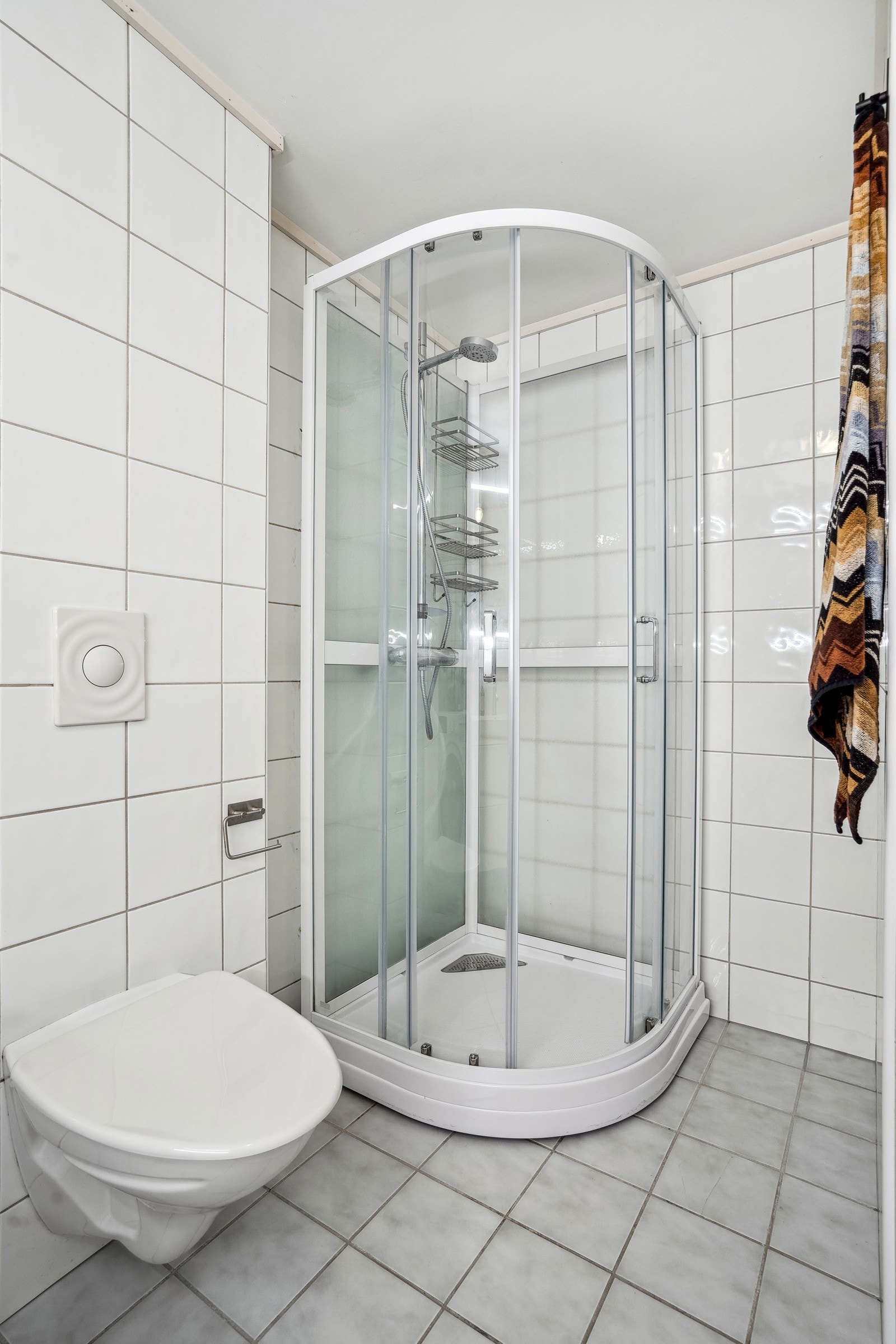 Moderne, flislagt bad, med varmekabler i gulv. Utstyrt med praktisk vegghengt wc og dusjkabinett. Galleribilde