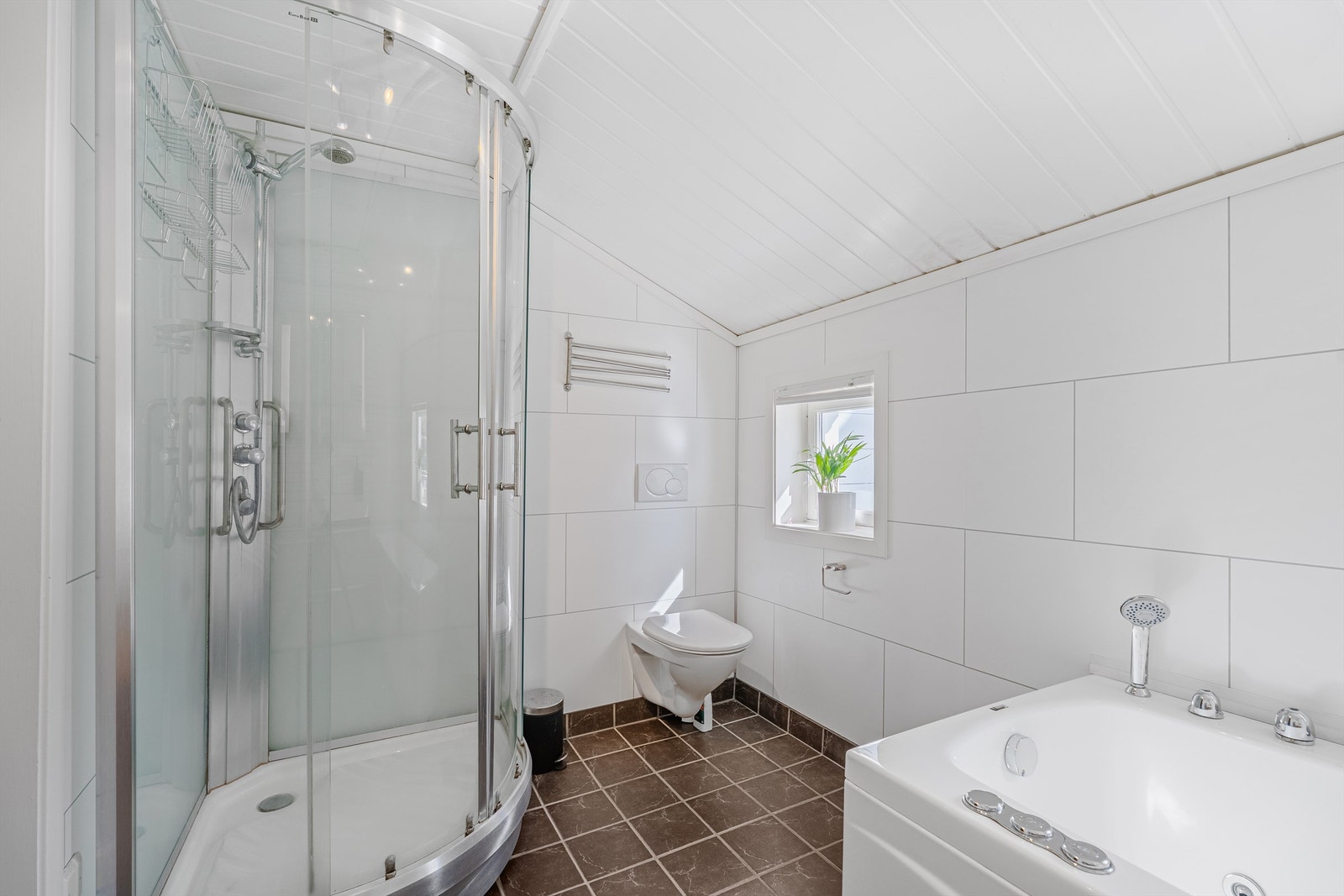Badet er innredet med dusjkabinett, badekar, wc og servant. Galleribilde