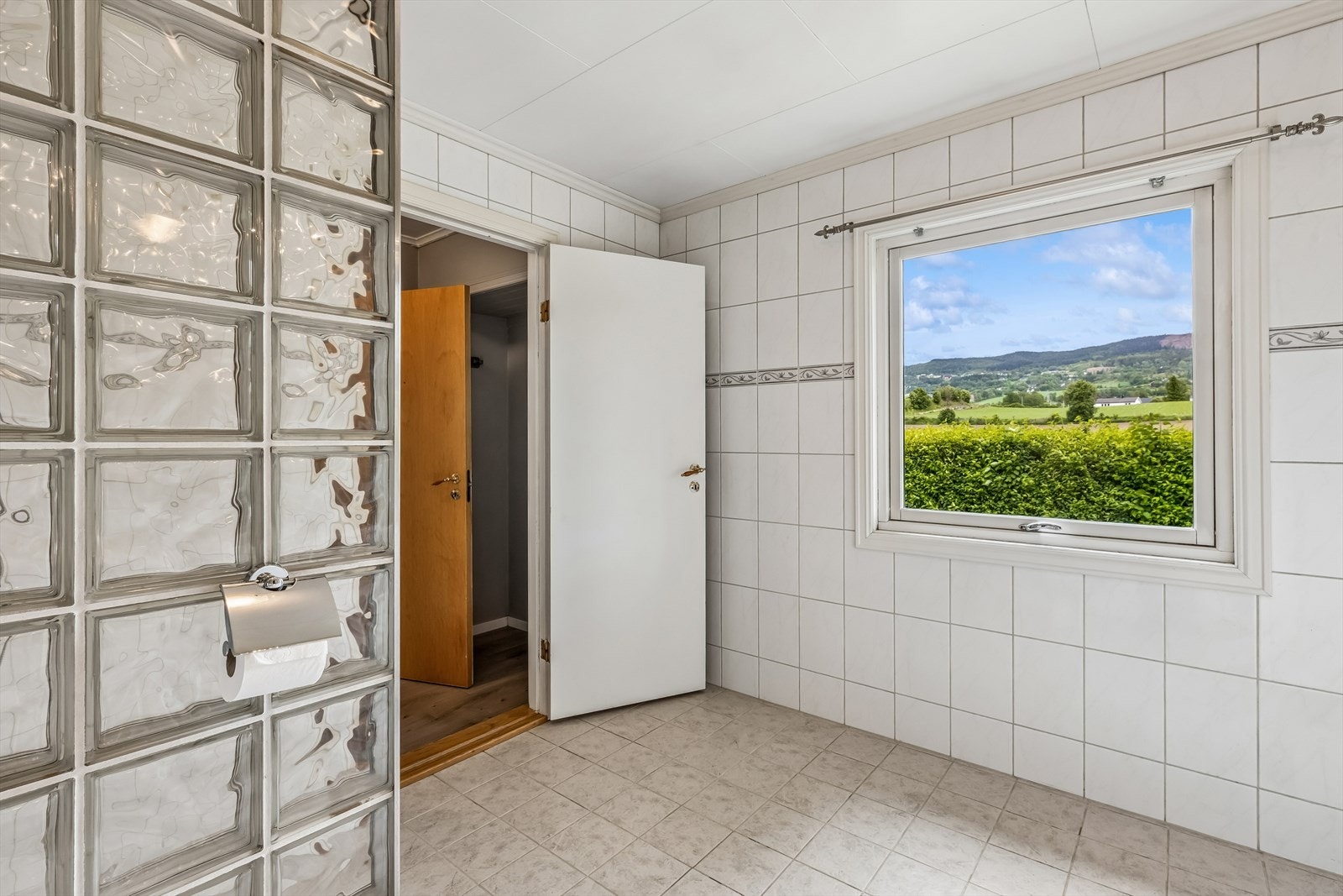 Dusjsonen er avskjermet med en vegg i glassbyggerstein, og det er opplegg for vaskemaskin. Galleribilde