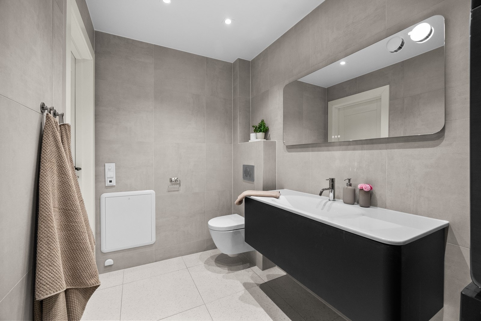 Badet har en moderne innredning med vegghengt toalett og servantskap som gir gode oppbevaringsmuligheter. Fordelerskapet for rør-i-rør systemet er også plassert i rommet. Galleribilde