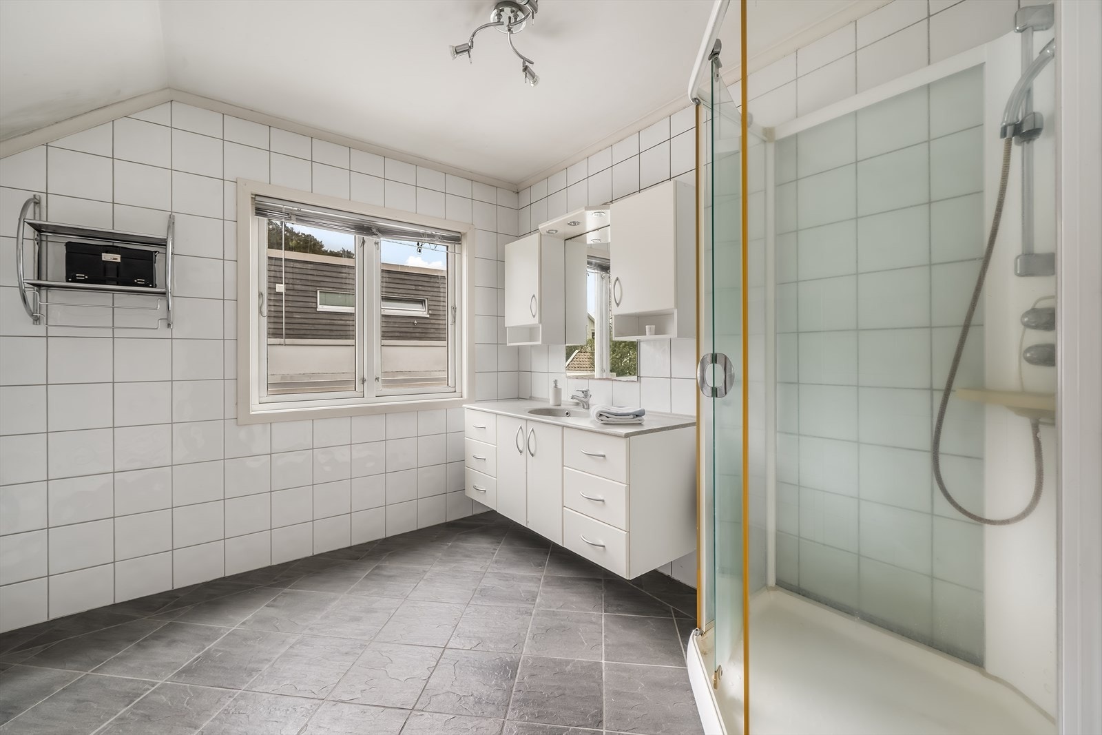 Badet på loftet er flislagt og utstyrt med både dusjkabinett og badekar. Galleribilde