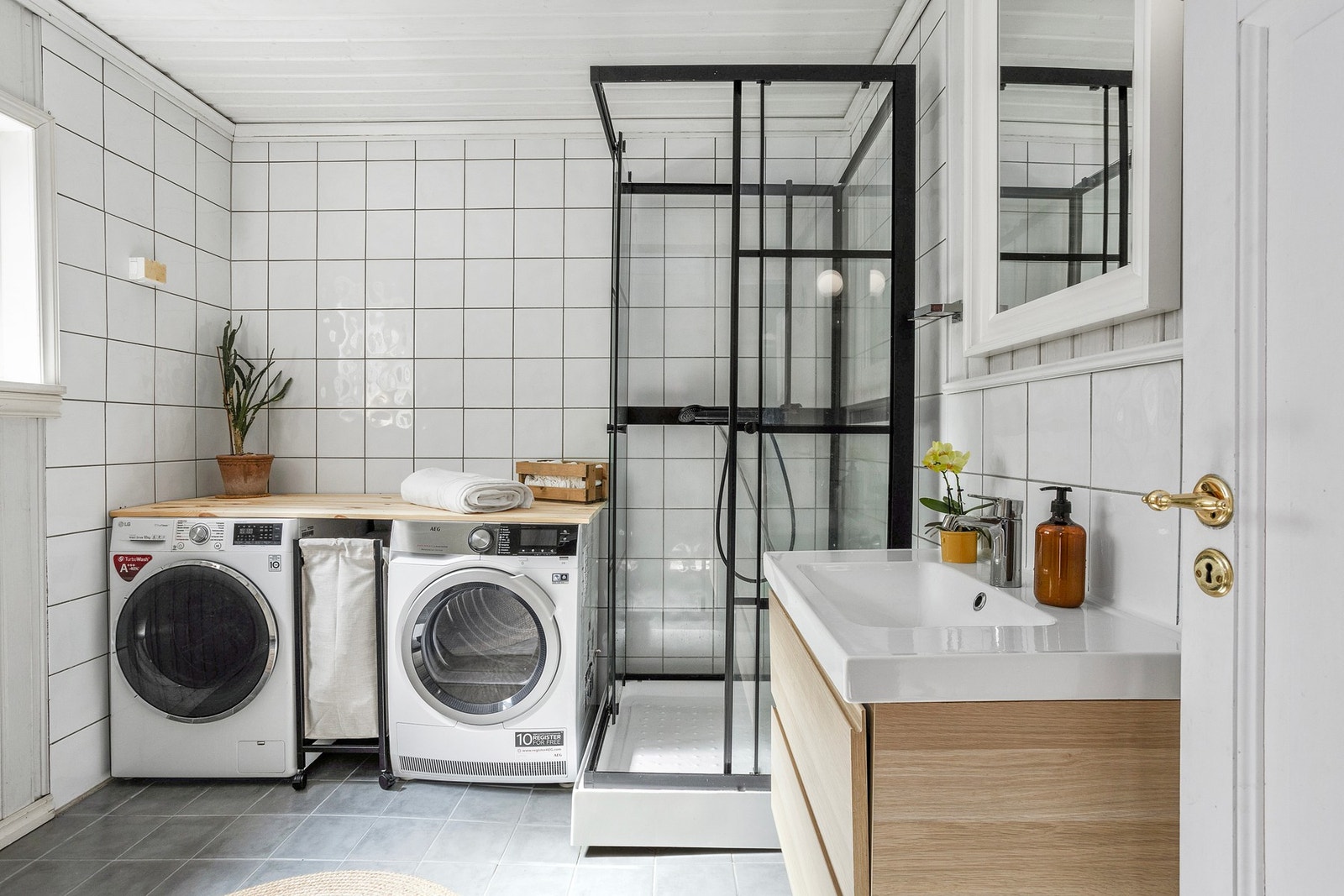 Badet er innredet med vegghengt servantskap med ovenpåliggende servant, dusjkabinett, gulvstående toalett og opplegg for vaskemaskin Galleribilde