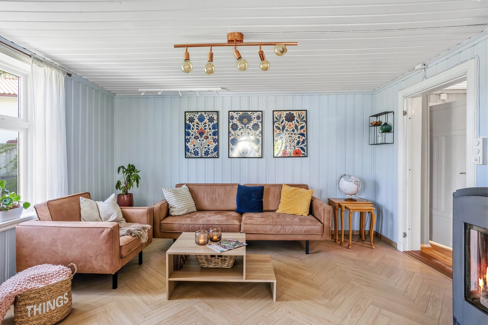Innbydende stue og spisestue med fiskebenslaminat på gulv, malt panel på veggene og panel i himlingen Galleribilde