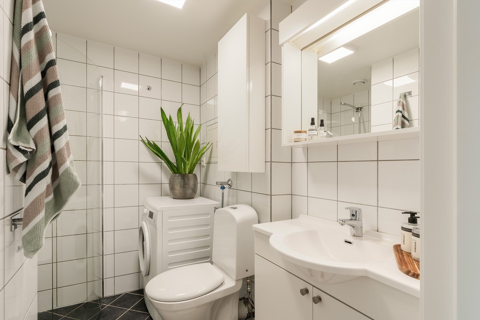 Flislagt bad med behagelig gulvvarme og praktisk opplegg for vaskemaskin. Galleribilde