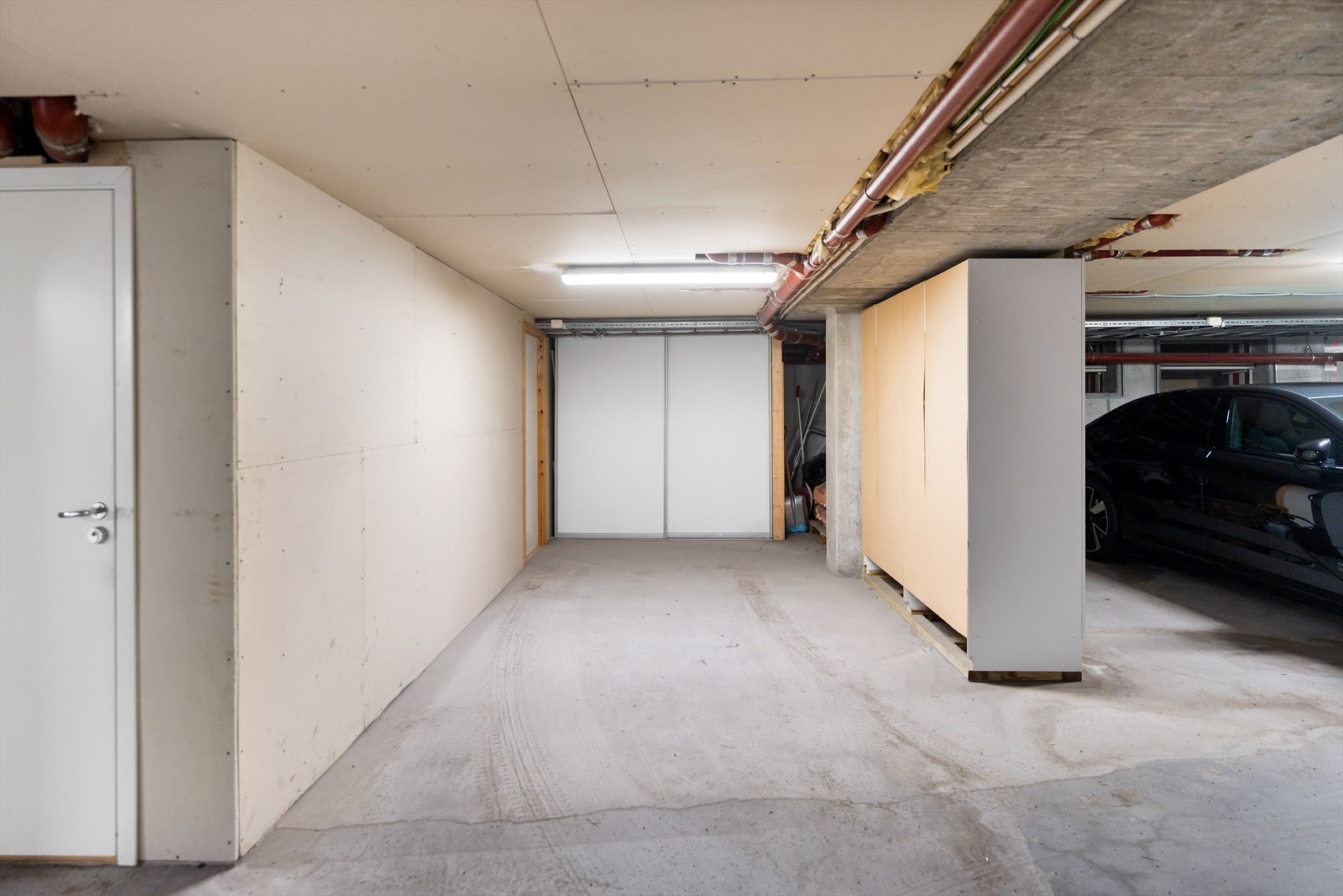 Bod innerst til venstre og parkering i felles garasje. Skyvedører for lagring rett frem i bildet Galleribilde
