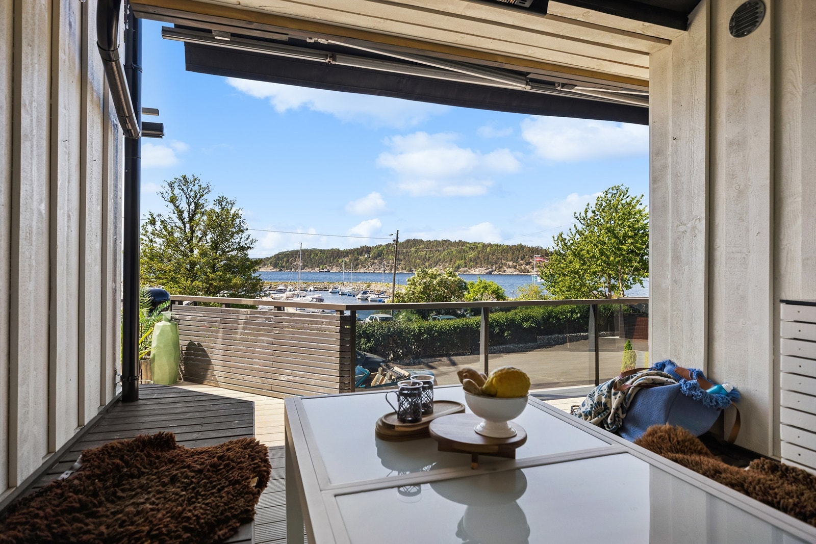 En av boligens mange uteplasser - overbygget med markise og med nydelig utsikt over fjorden. Glassrekkverket åpner mot gårdsplassen, mens trerekkverket skjermer mot innsyn og skaper en lun og privat atmosfære. Galleribilde