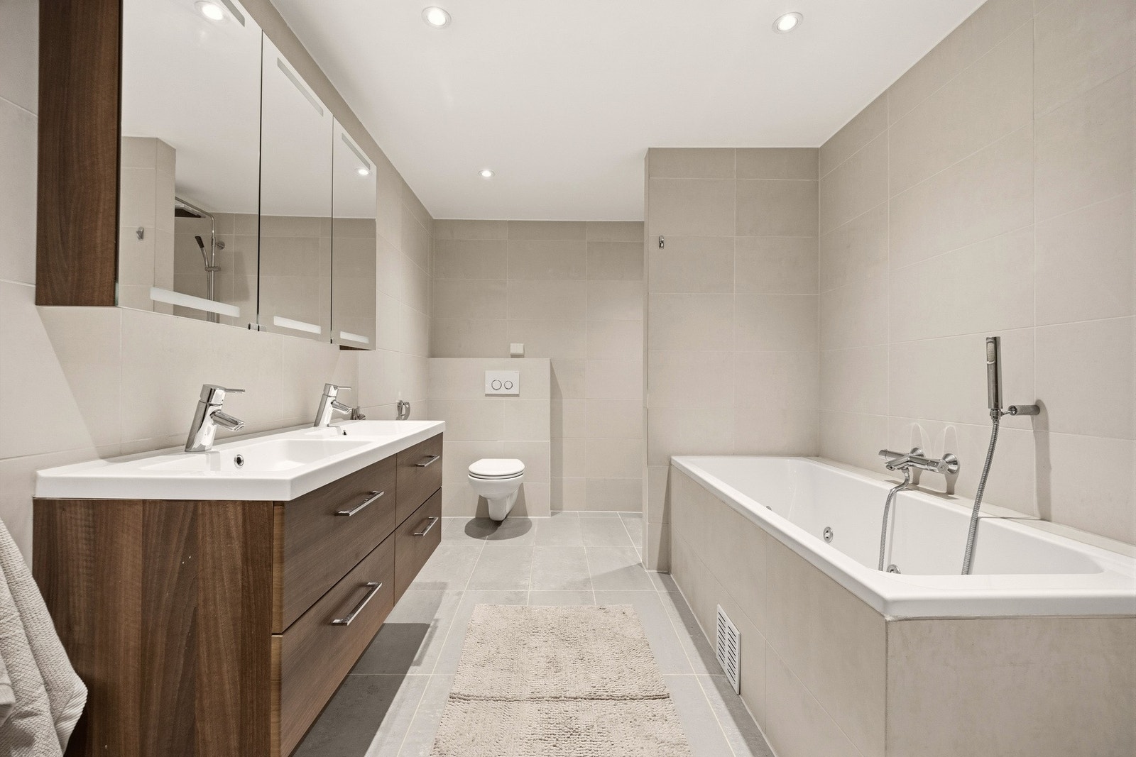 Badet er innredet med lyse fliser på gulv og vegger, samt downlights i himlingen. Galleribilde