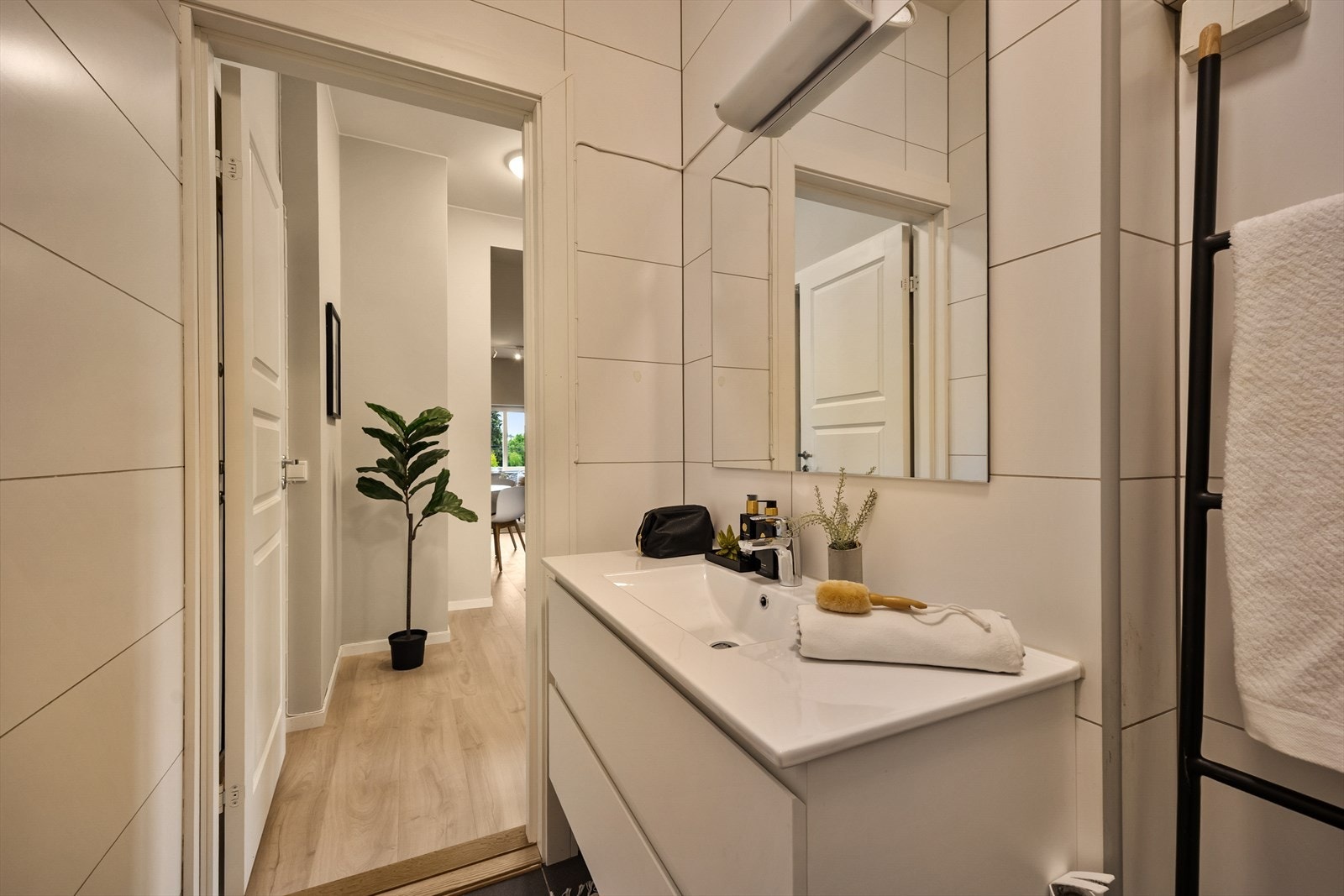 Lyst baderom med vegghengt toalett, servantinnredning og opplegg for vaskemaskin. Galleribilde