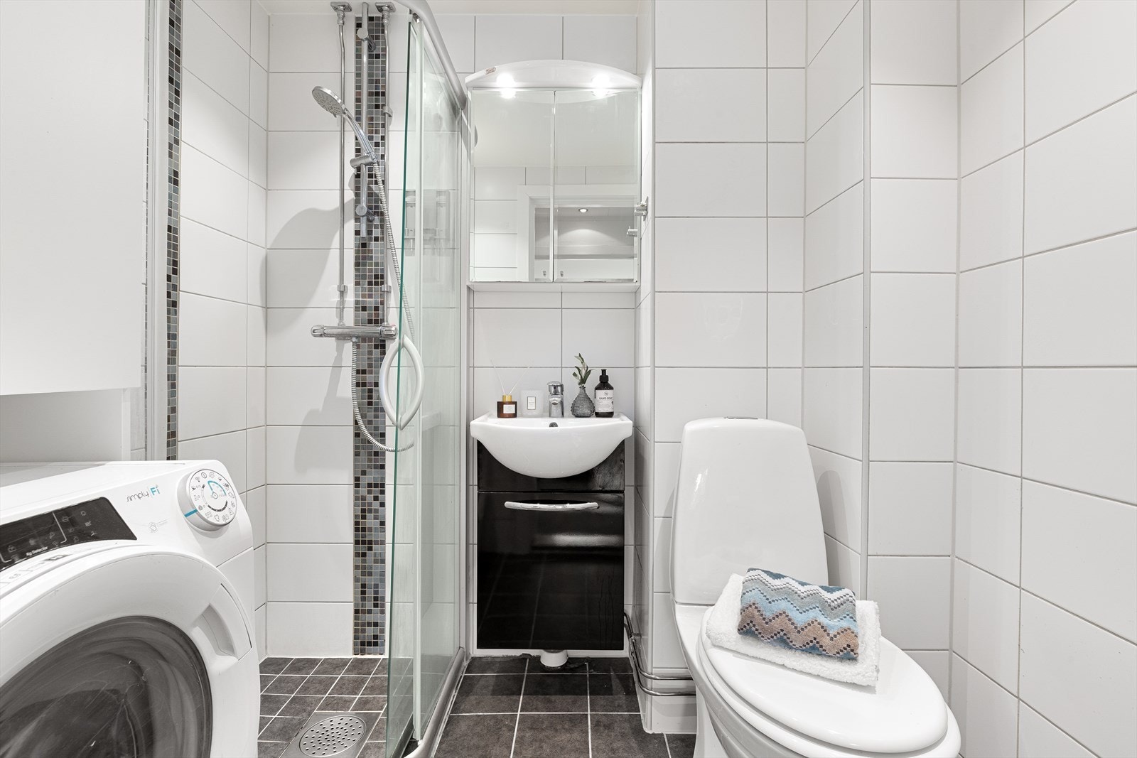 Badet har flislagte vegger og gulv med elektriske varmekabler samt dusjhjørne med glassdører. Galleribilde