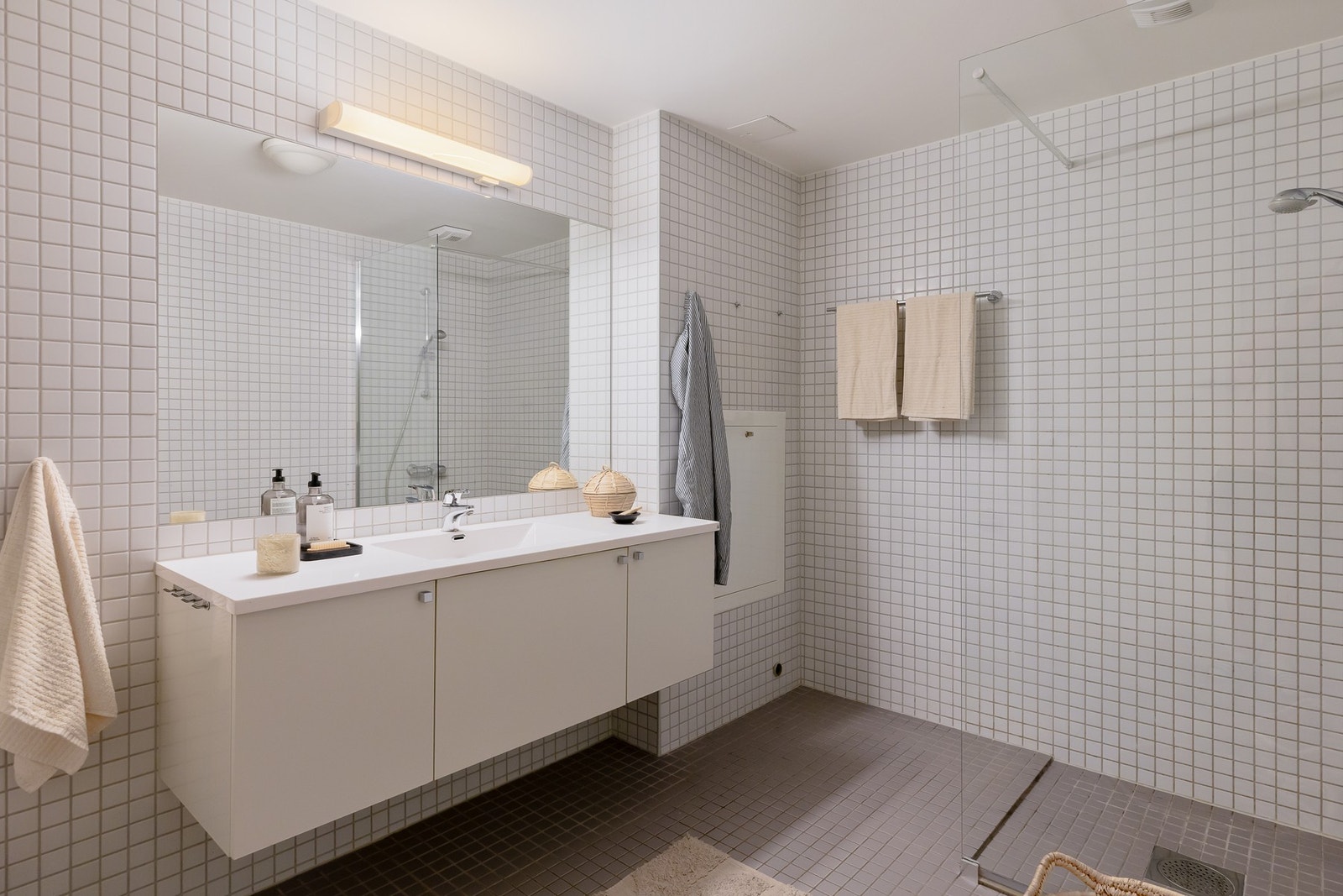 Badet er innredet med vegghengt servant med armatur, speil med overlys, gulvstående høyskap, dusjnisje med glassvegg, samt vegghengt toalett. Galleribilde