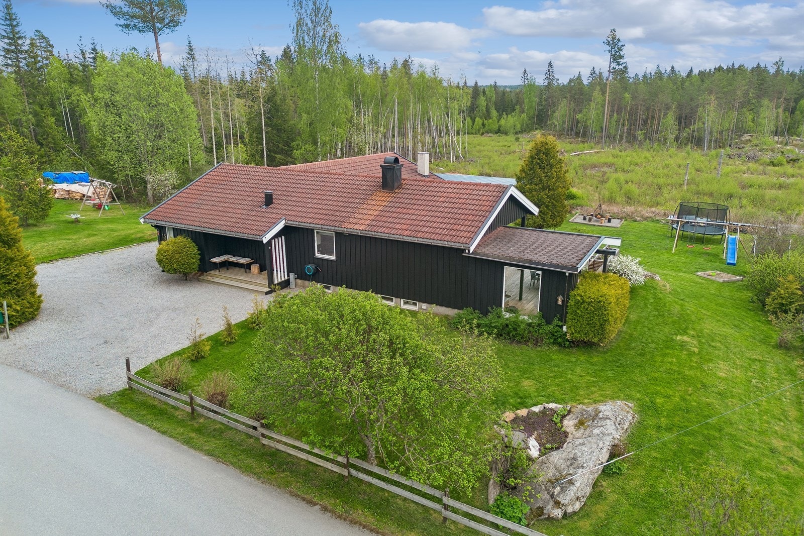Tomten er lett hellende med grense til skogareal, frodig hage med store plenarelaer og variert beplantning. Galleribilde