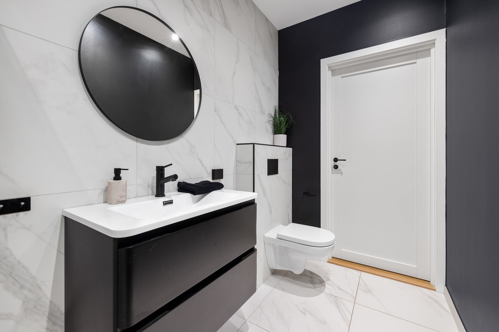 Badet nede har downlightsbelysning, marmorerte gulv- og veggfliser og sorte veggflater som matcher interiøret. Galleribilde