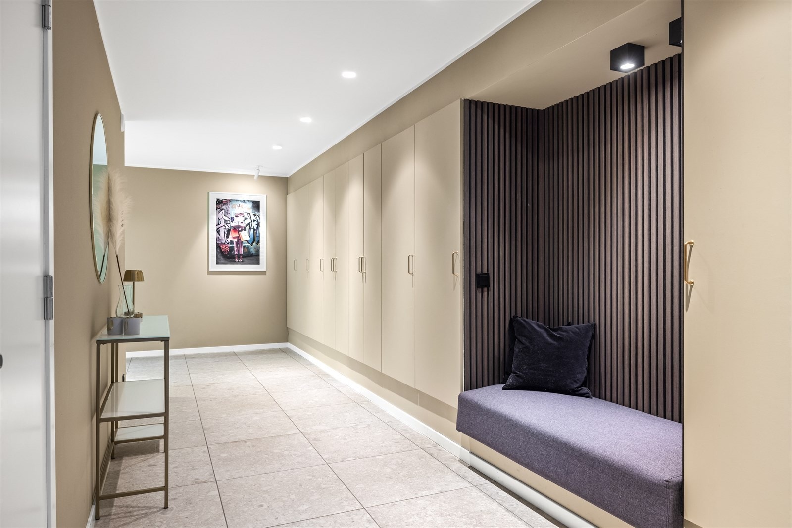 Hall med innfelt garderobeløsning og en spesialdesignet nisje med mørk spilevegg og innebygd sittebenk. Galleribilde