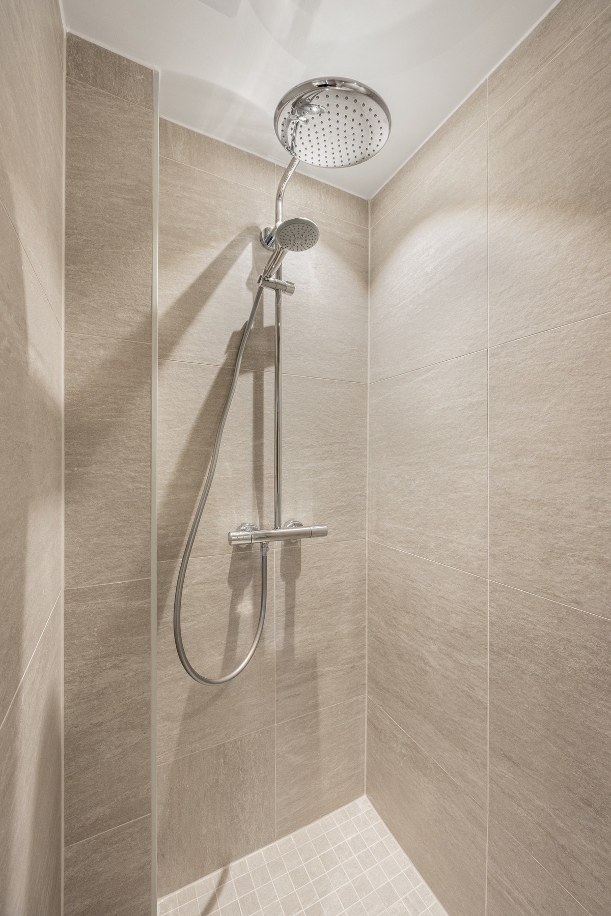 Badet er utstyrt med regnfallsdusj, vegghengt toalett og varmekabler for optimal komfort. Galleribilde