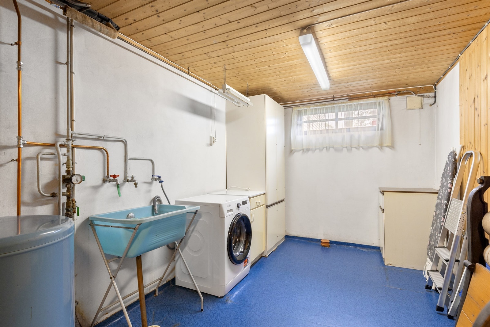 Stort vaskerom i kjeller med opplegg for vaskemaskin, varmtvannsbereder, utslagsvask og eldre vaskeromsinnredning Galleribilde