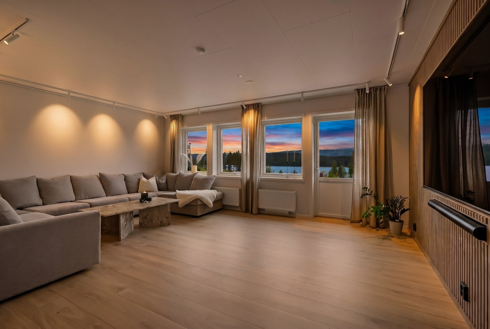Overflatene er holdt i nøytrale, lyse fargetoner med laminatgulv og en lekker spilevegg som understreker boligens moderne interiør. Galleribilde