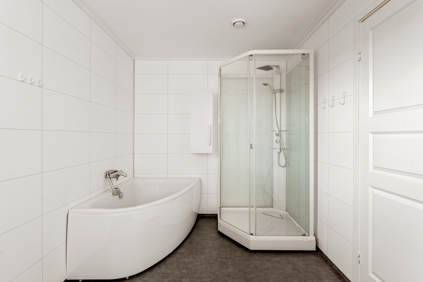 Badet er innredet med servantinnredning, vegghengt toalett, dusjkabinett samt badekar. Galleribilde