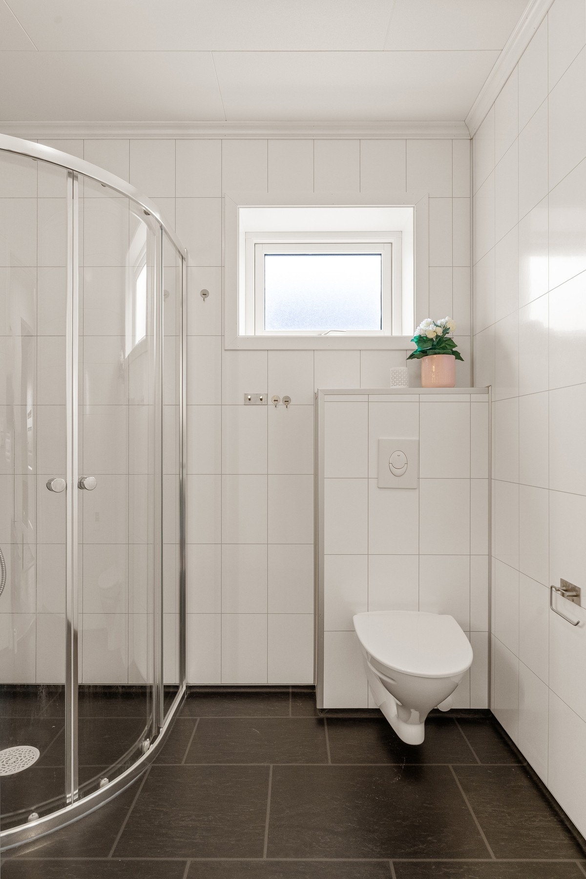 Badet er utstyrt med servantinnredning, høyskap, dusjhjørne og vegghengt toalett. Galleribilde