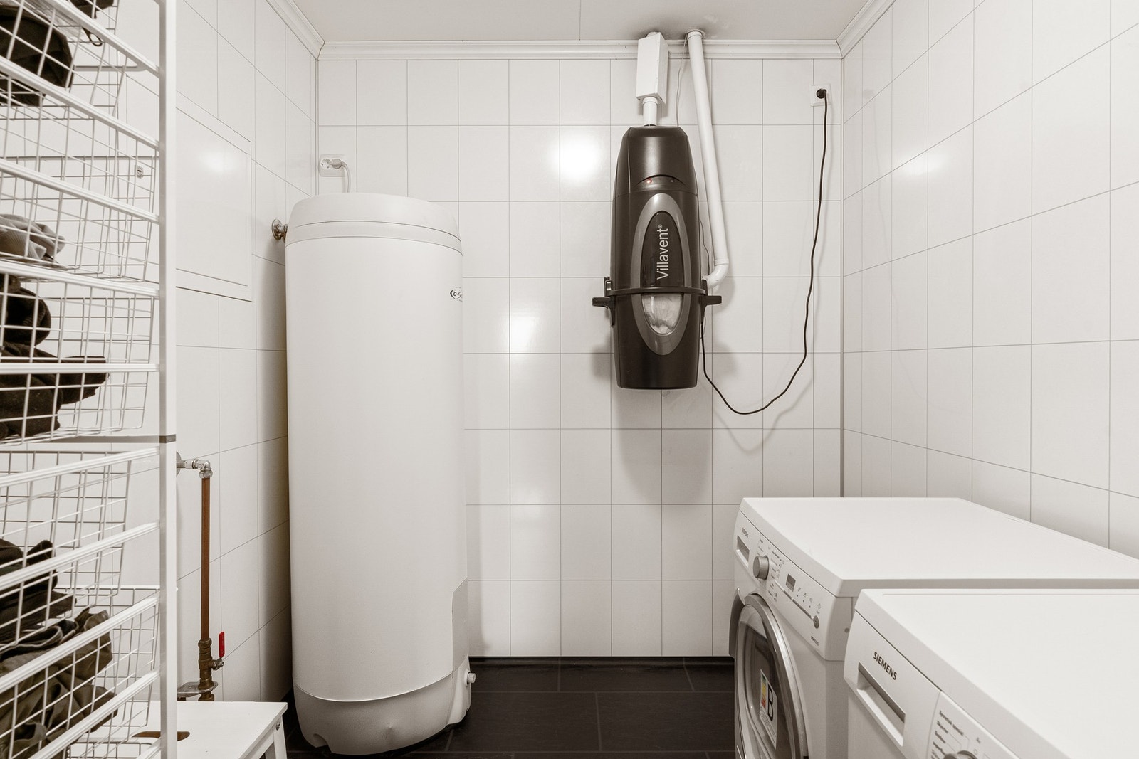 En av boligens boder benyttes som vaskerom med opplegg for vaskemaskin og plass til tørketrommel. Galleribilde