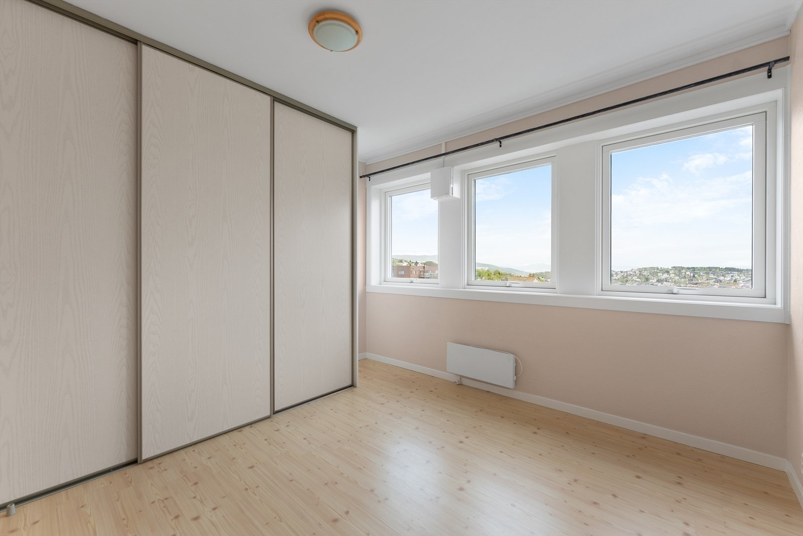 Soverom 1 - Innbydende soverom med god plass til møblering, skyvedørsgarderobe og flere vindusflater Galleribilde
