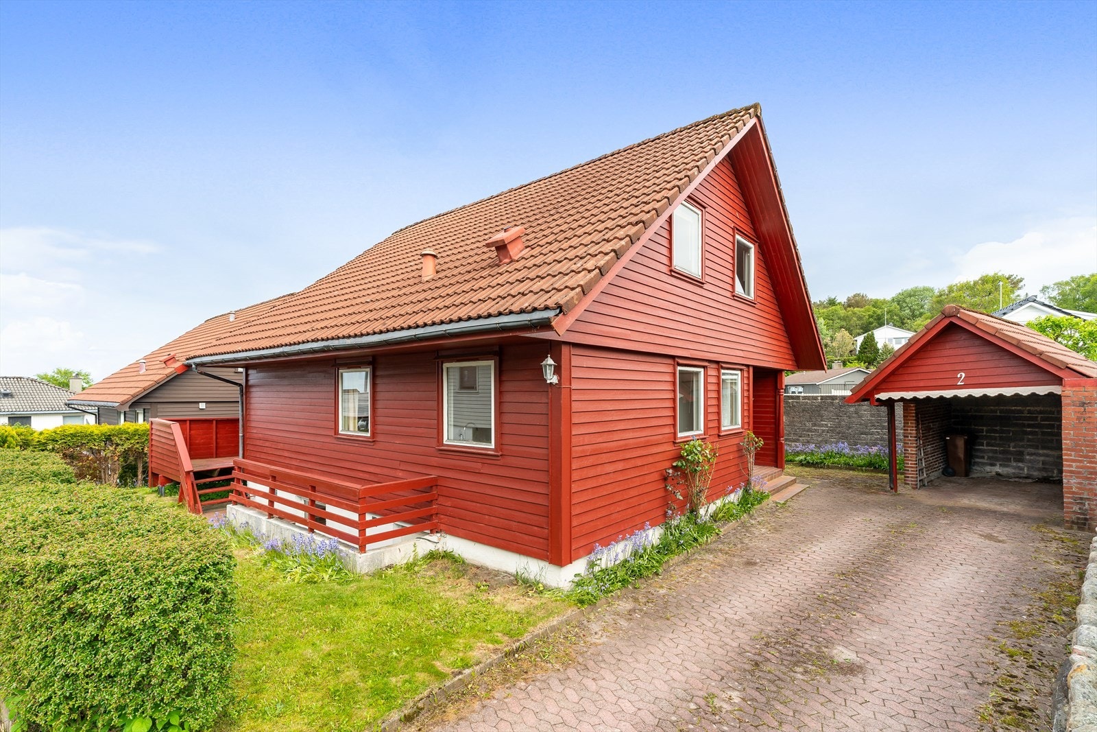 Enebolig over tre plan fra 1980 med frittstående carport og en flat, lettstelt tomt. Galleribilde