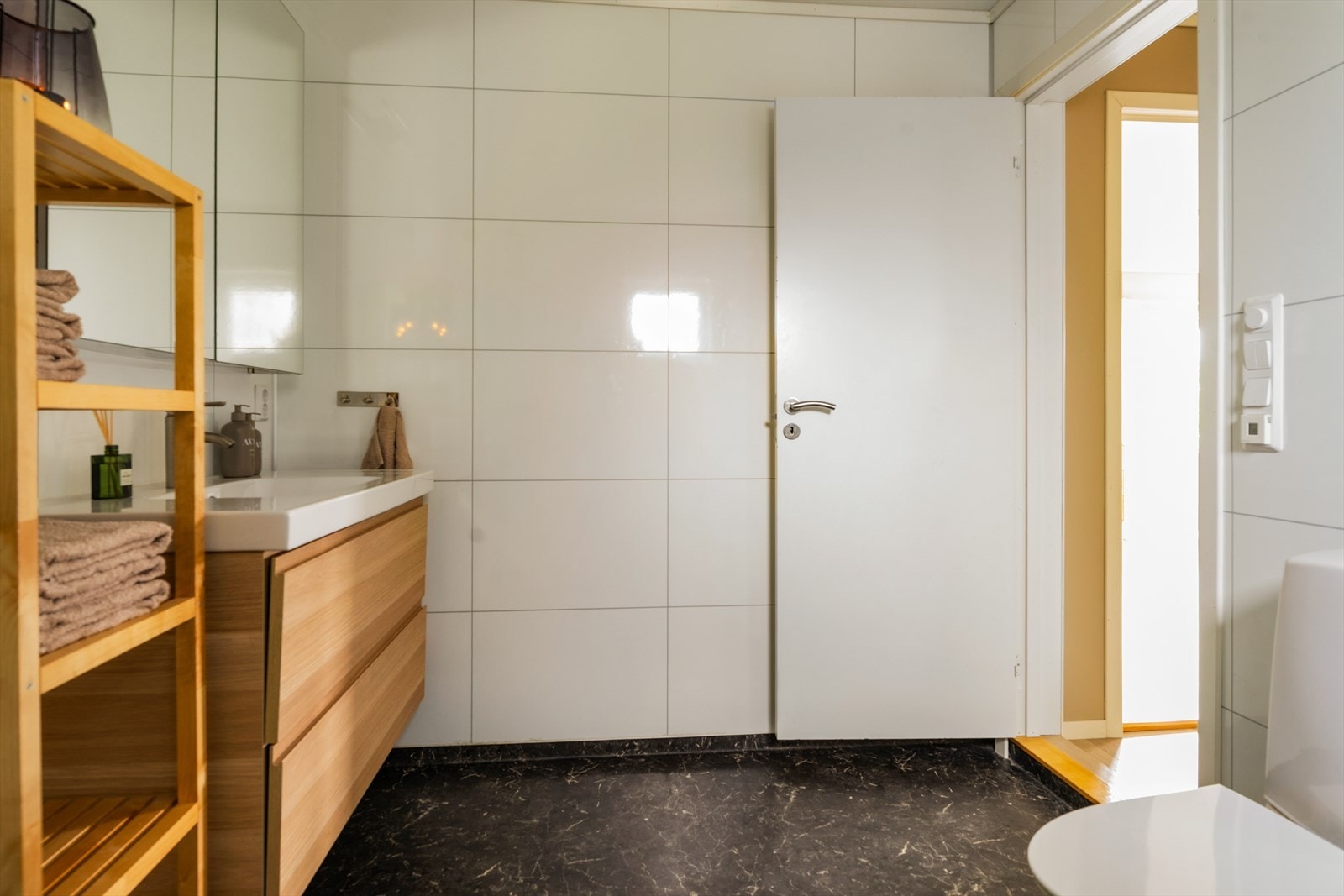Badet er innredet med baderomsinnredning med nedfelt servant, toalett, dusjvegger og opplegg for vaskemaskin Galleribilde