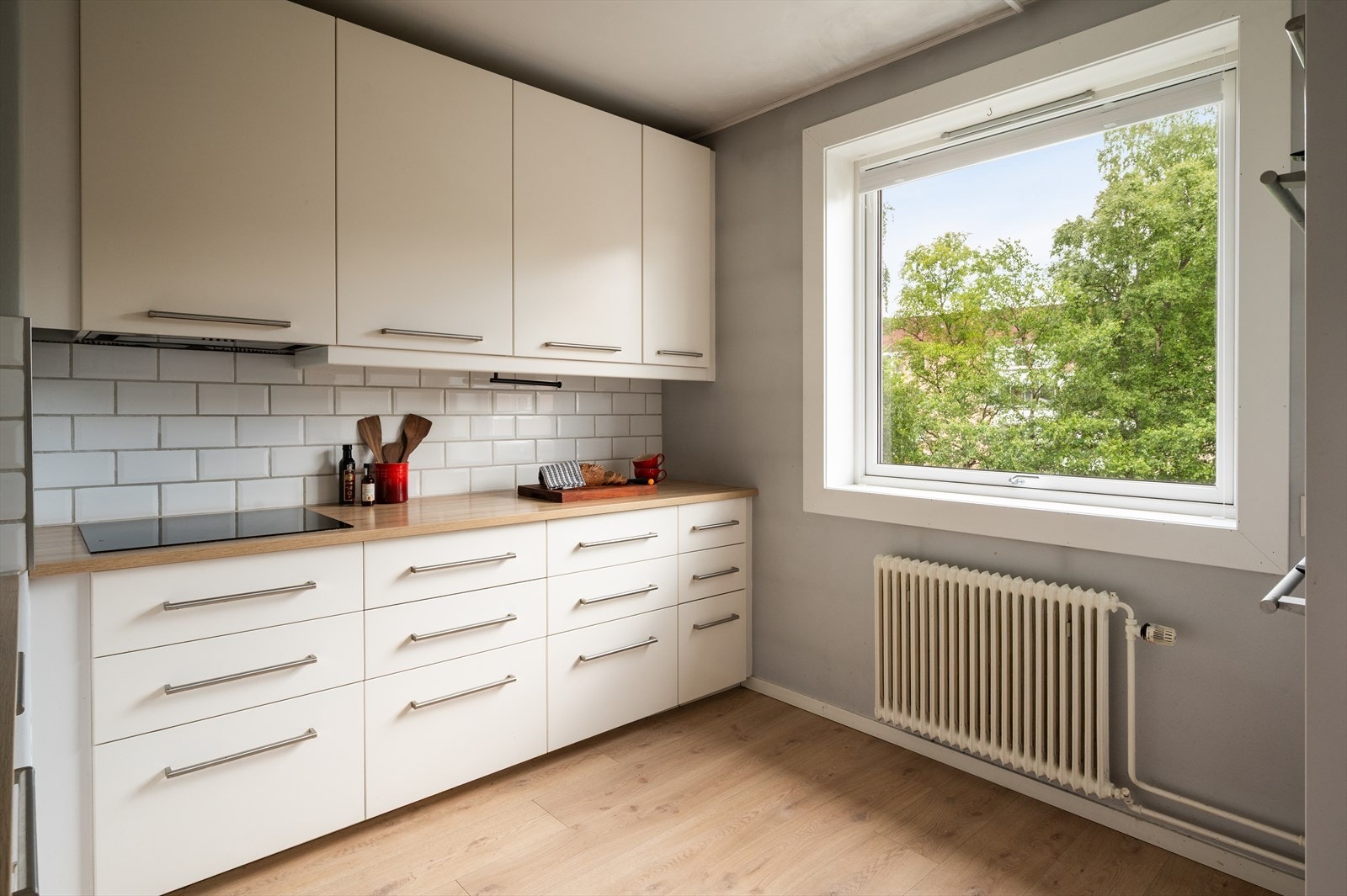 Kjøkkeninnredning med lyse, glatte fronter og laminat benkeplate med nedfelt vask-og skyllekum Galleribilde